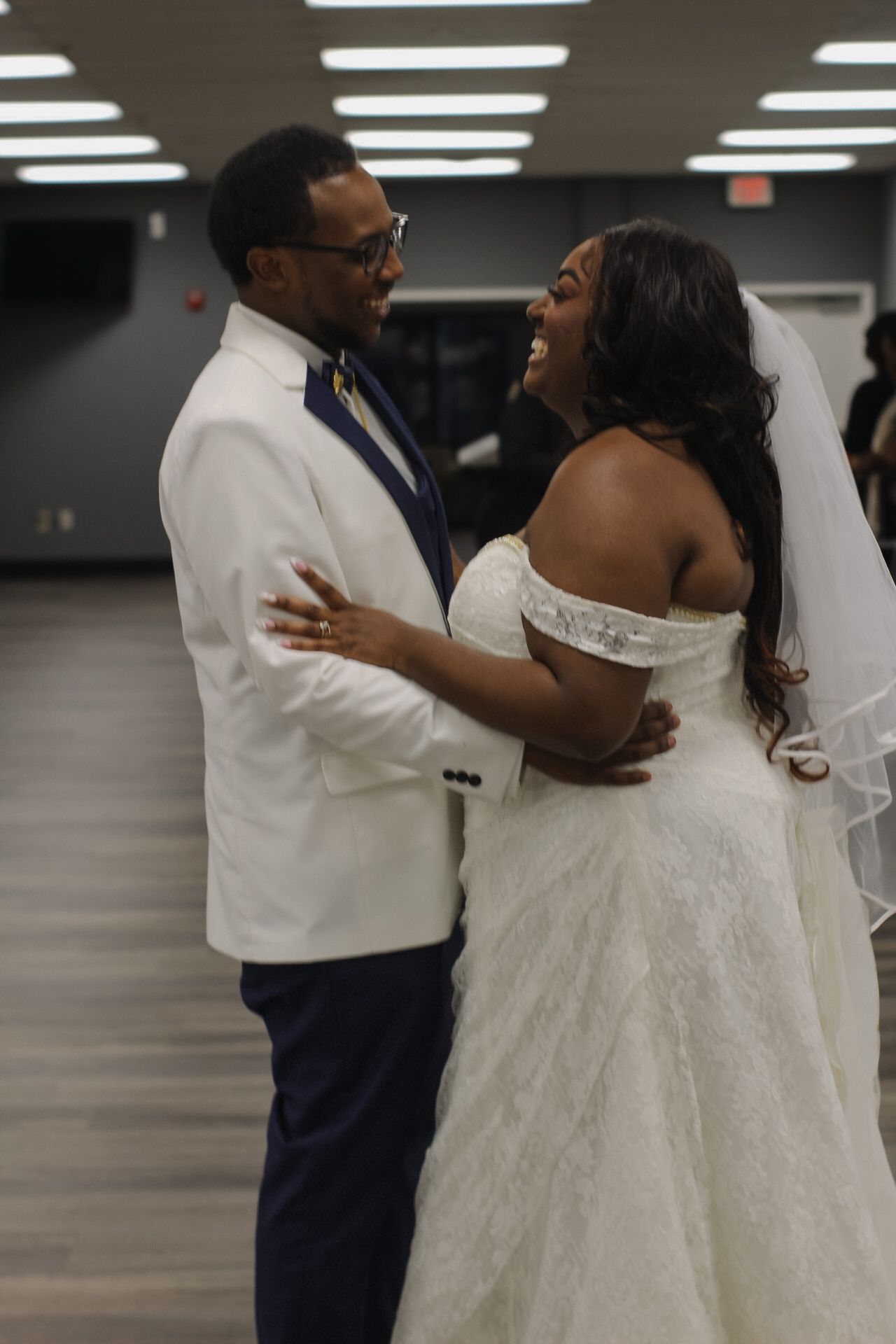 A joyful wedding moment shows a couple sharing a dance in a reception hall.