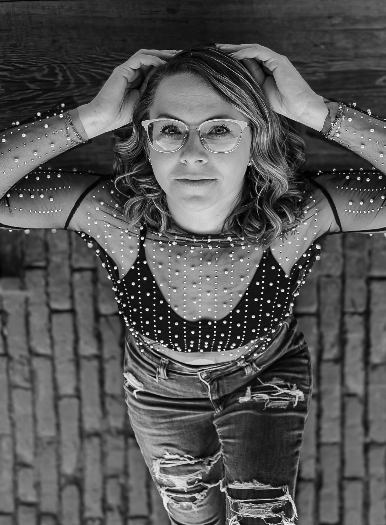 Black and white overhead shot showcasing mesh top and ripped jeans against wooden background.