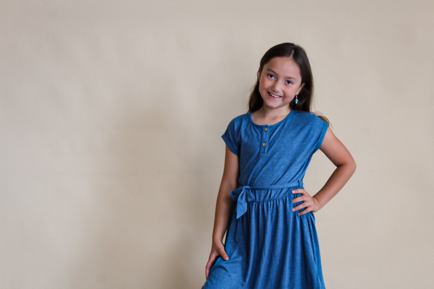 Portrait series showing playful poses in blue dress against neutral studio background.