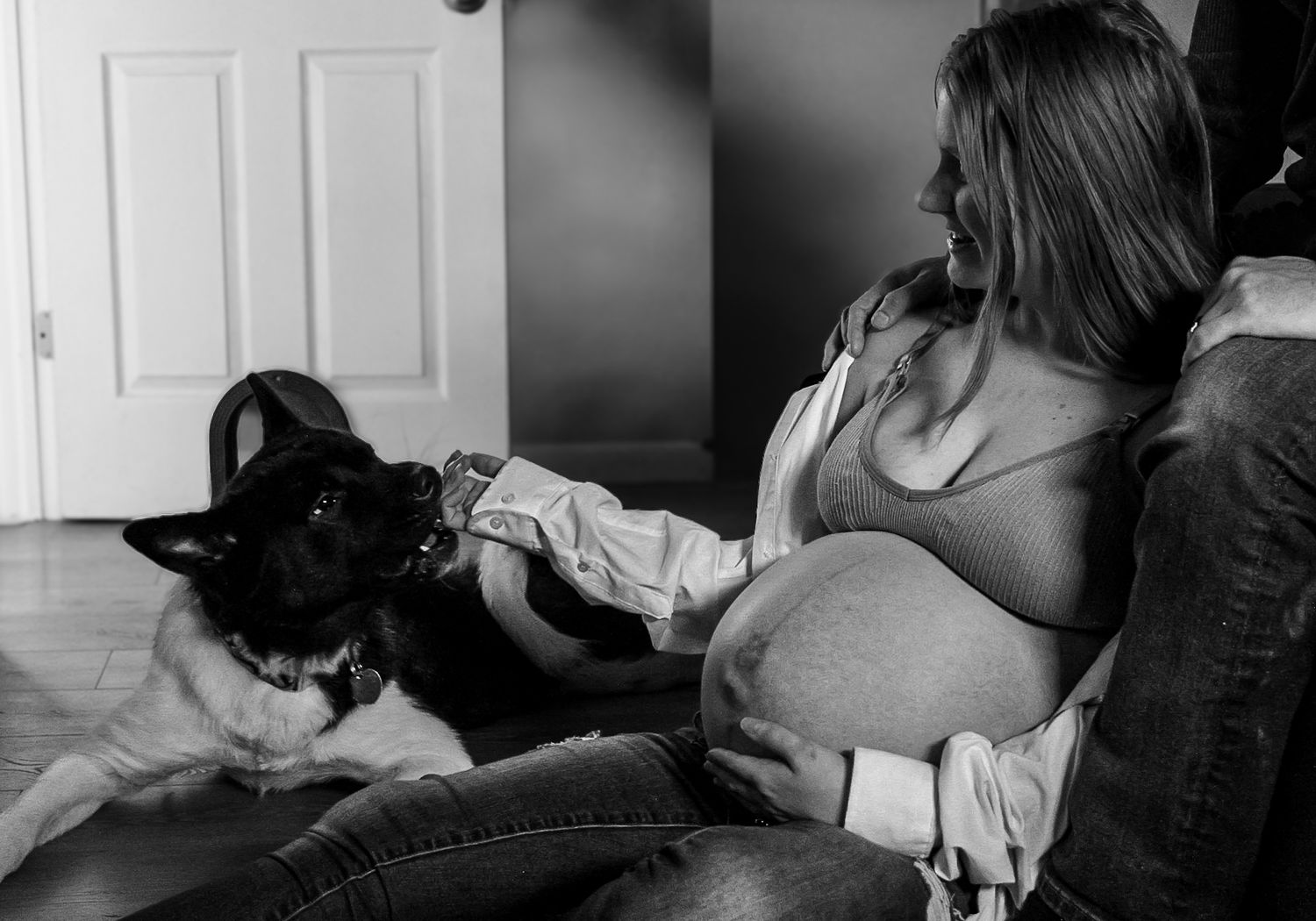 A pregnant person relaxes in a chair with a black and white cat nearby.