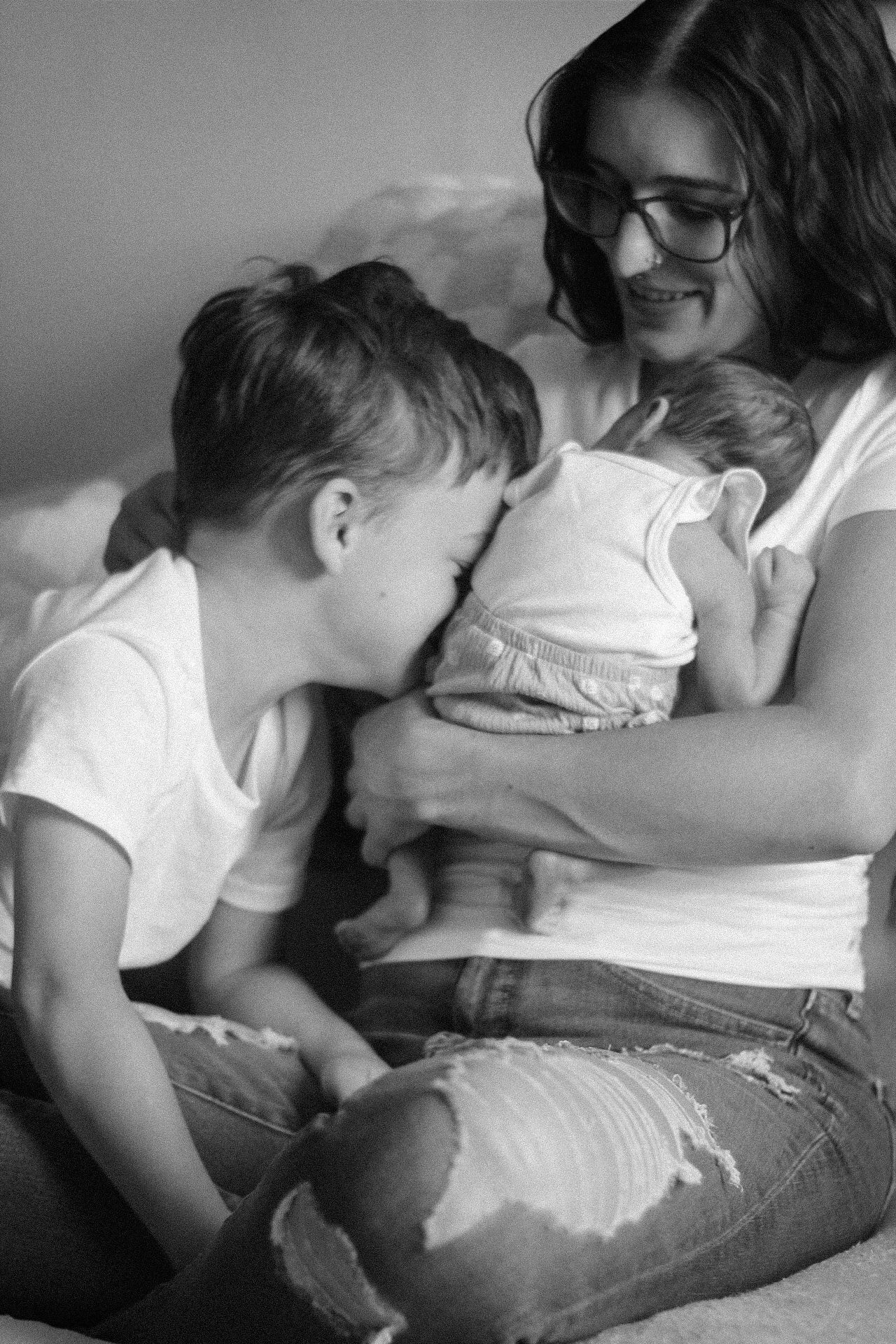 Black and white photo showing tender family moment on couch with infant.