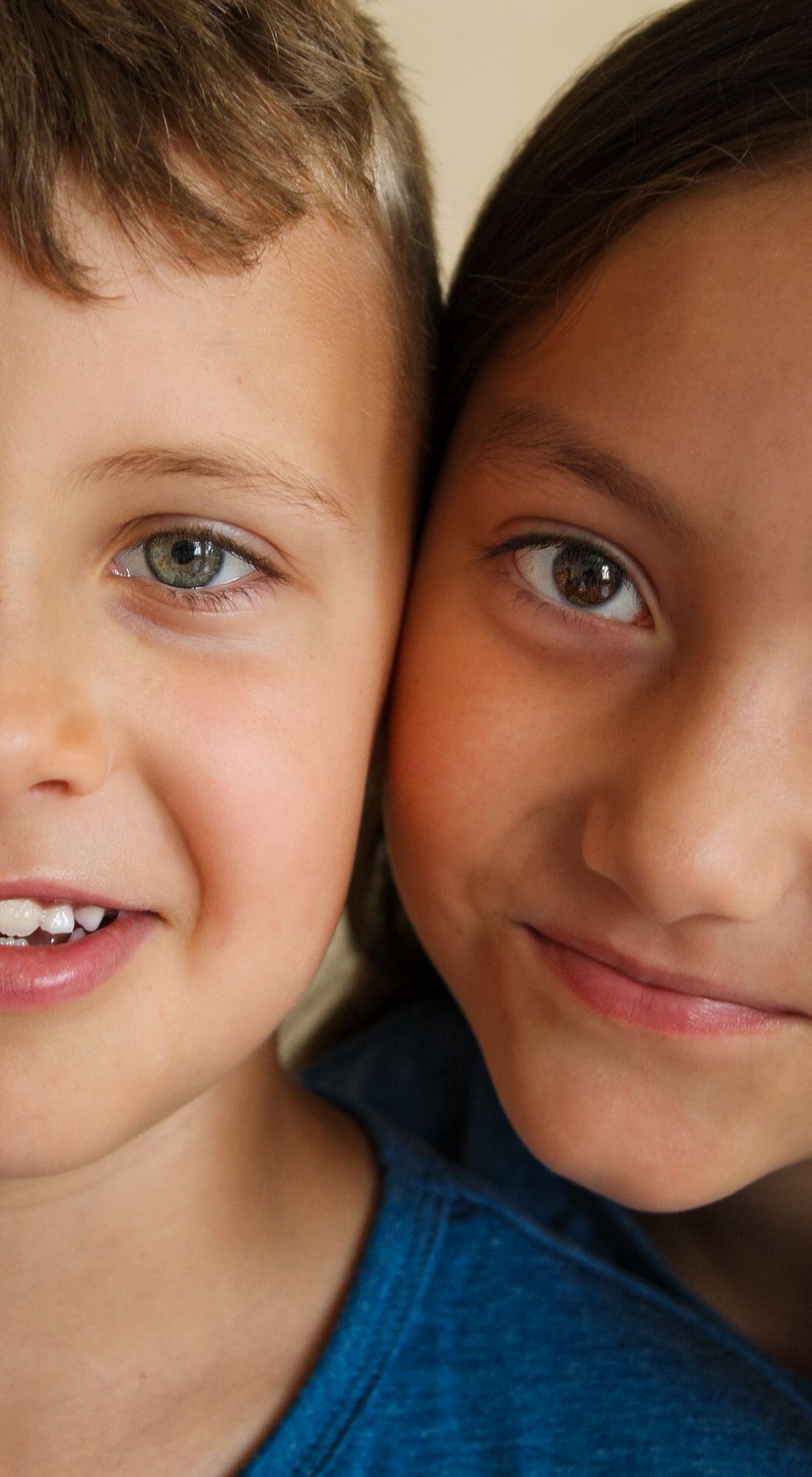 Two young smiling faces close together showing friendship and joy.