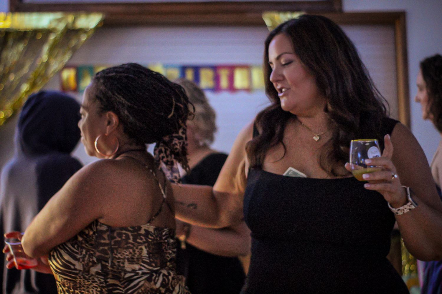 Two partygoers dance together at a celebration in a dimly lit room.