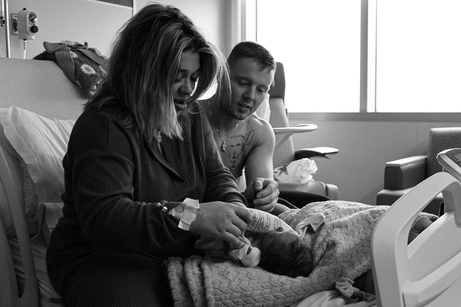 Family members gathered around a hospital bed sharing a quiet moment with a newborn.