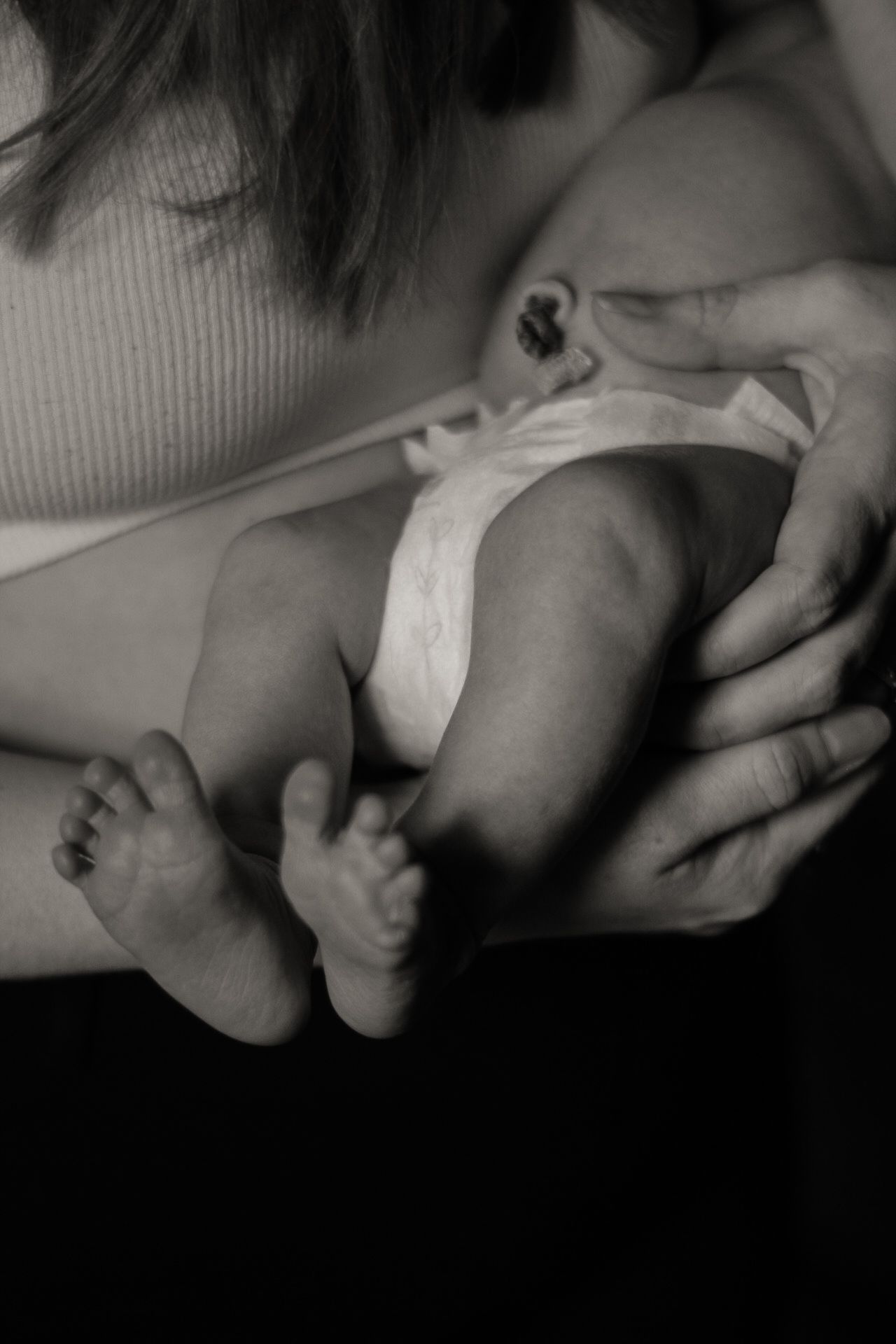 Black and white image of tiny baby feet with hands gently holding them.