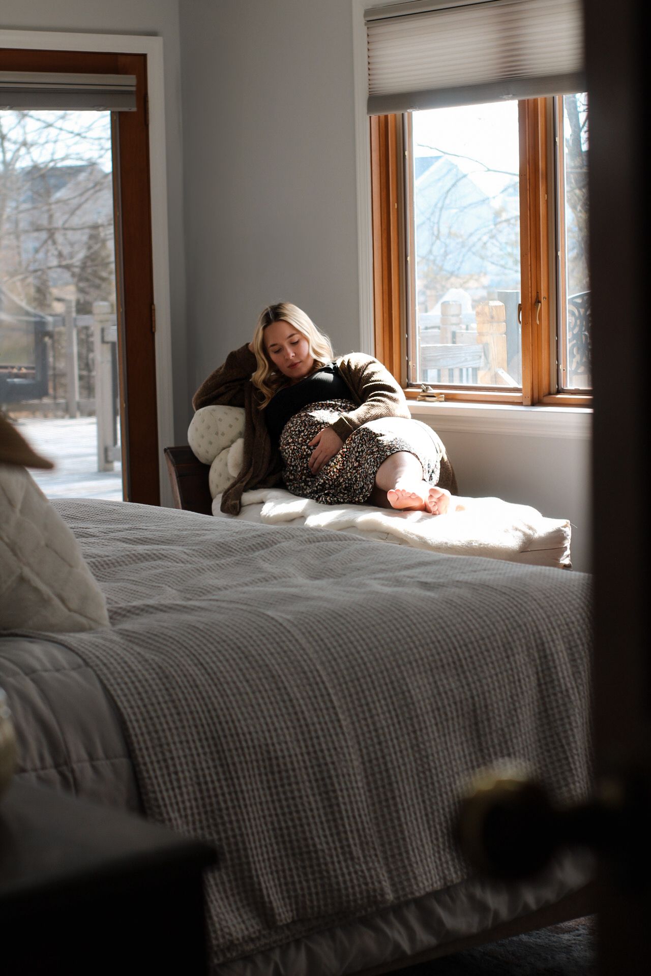 Person relaxing on bed near window with natural light streaming in.