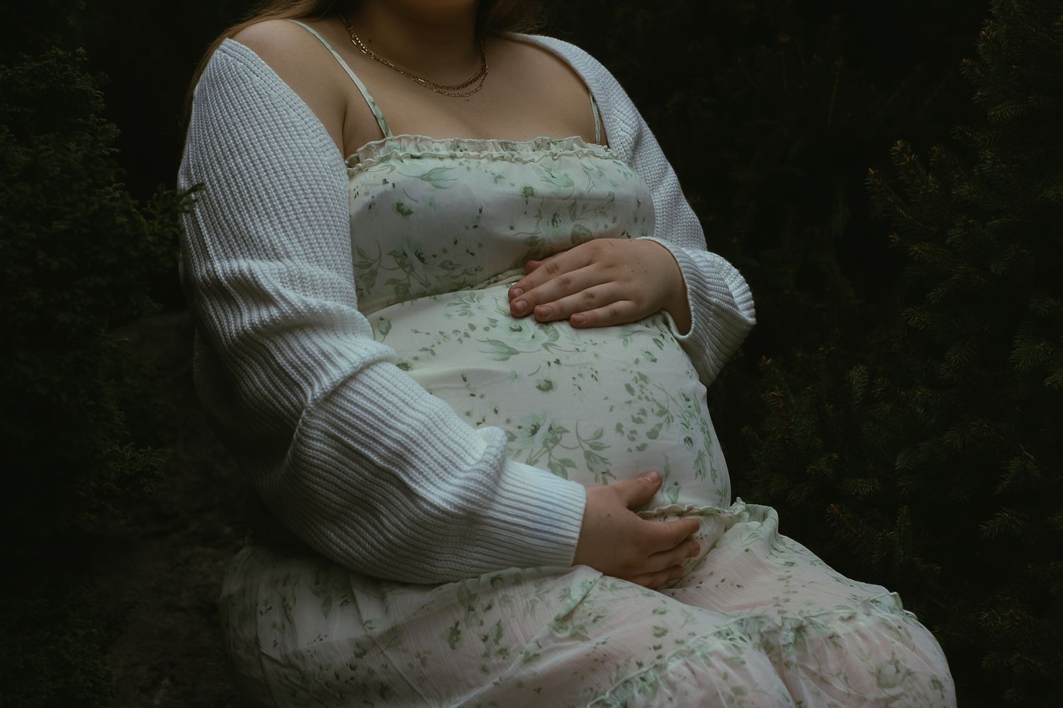 A floral dress and white sweater detail against a dark background.