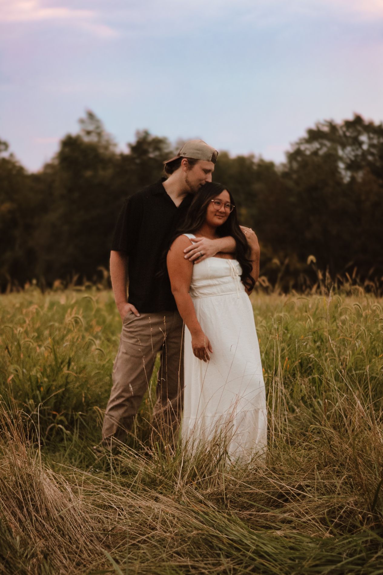 A couple embraces in a golden field during sunset creating a romantic silhouette against the warm sky.