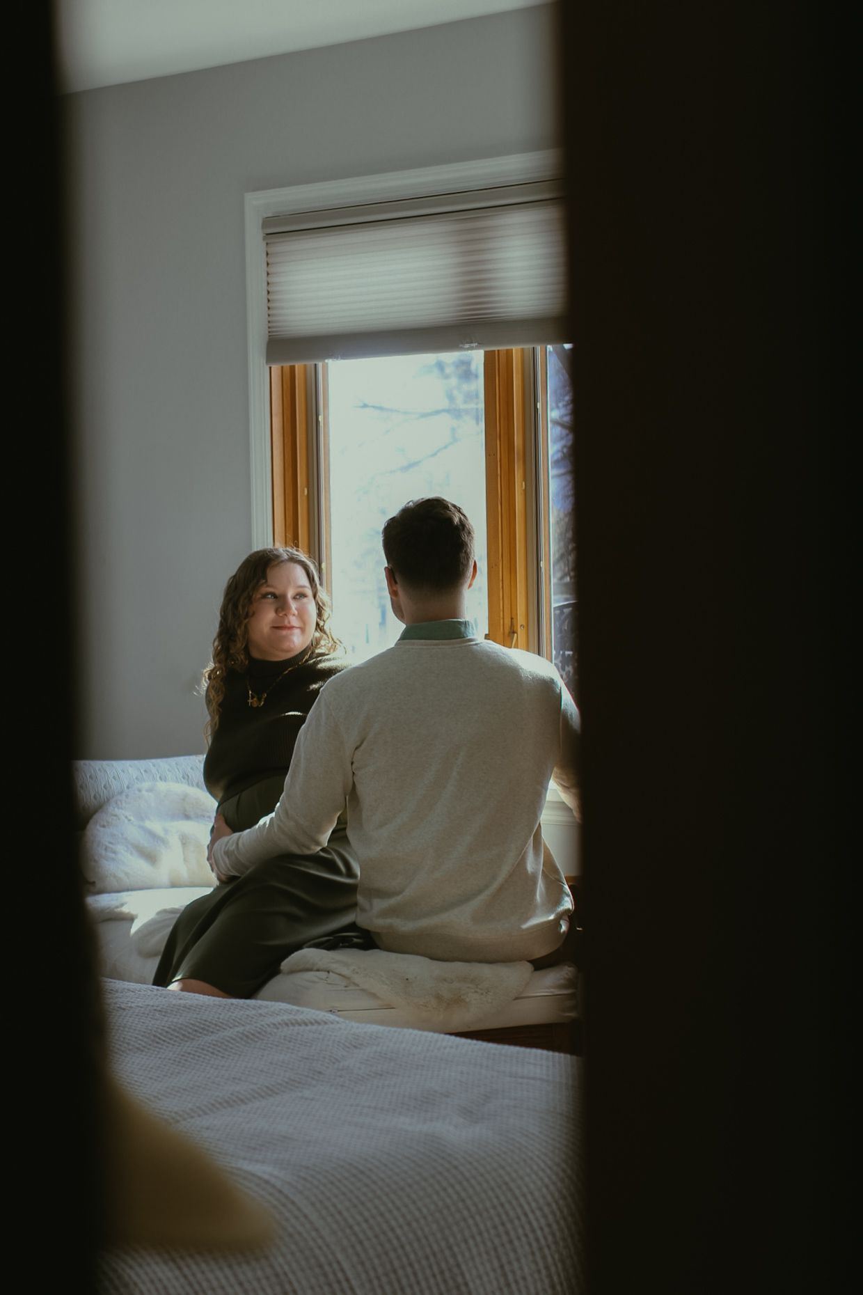 Silhouetted couple sitting by window in moody, intimate indoor setting.