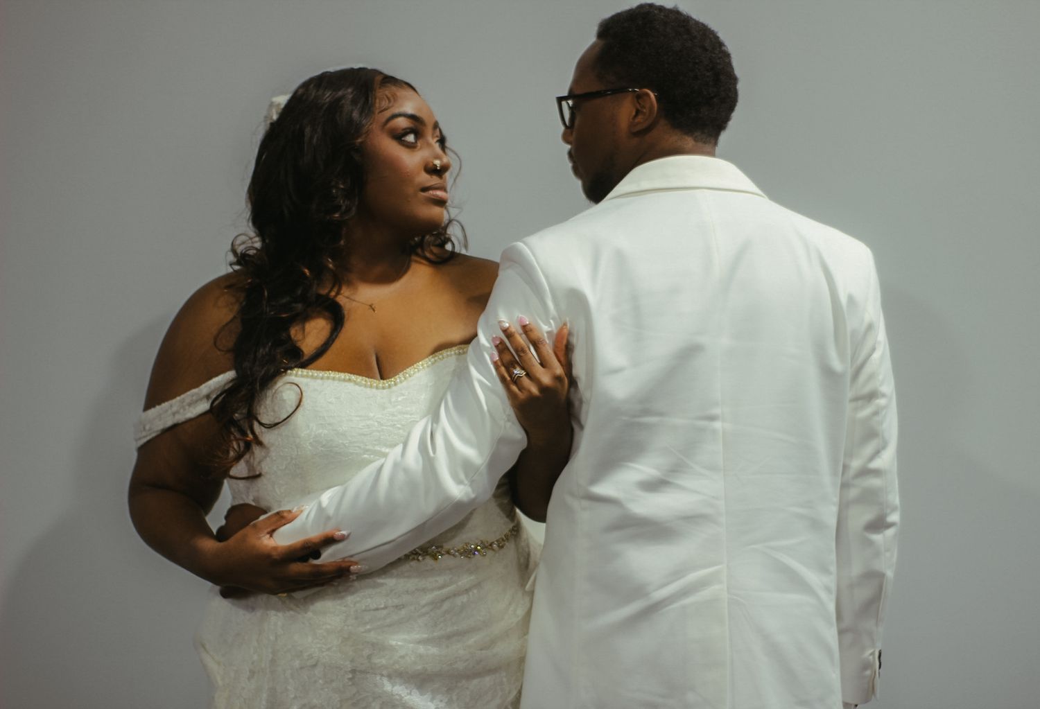 An elegant wedding portrait with soft lighting against a gray background.