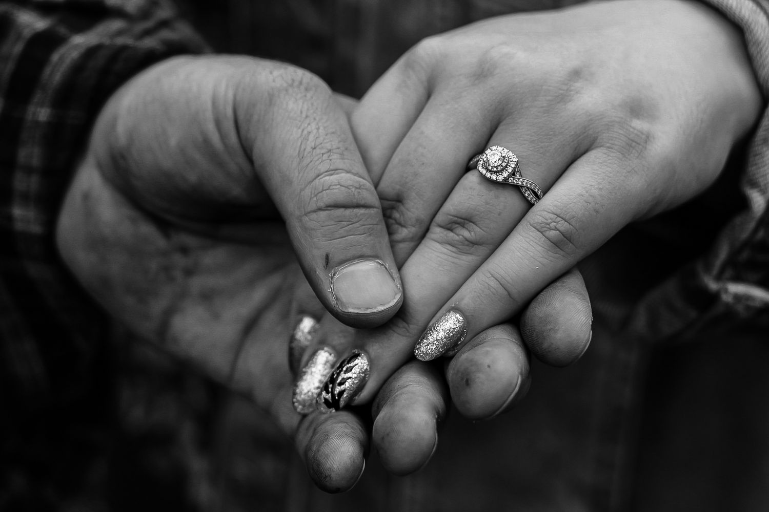 Close-up black and white shot of hands with engagement ring.