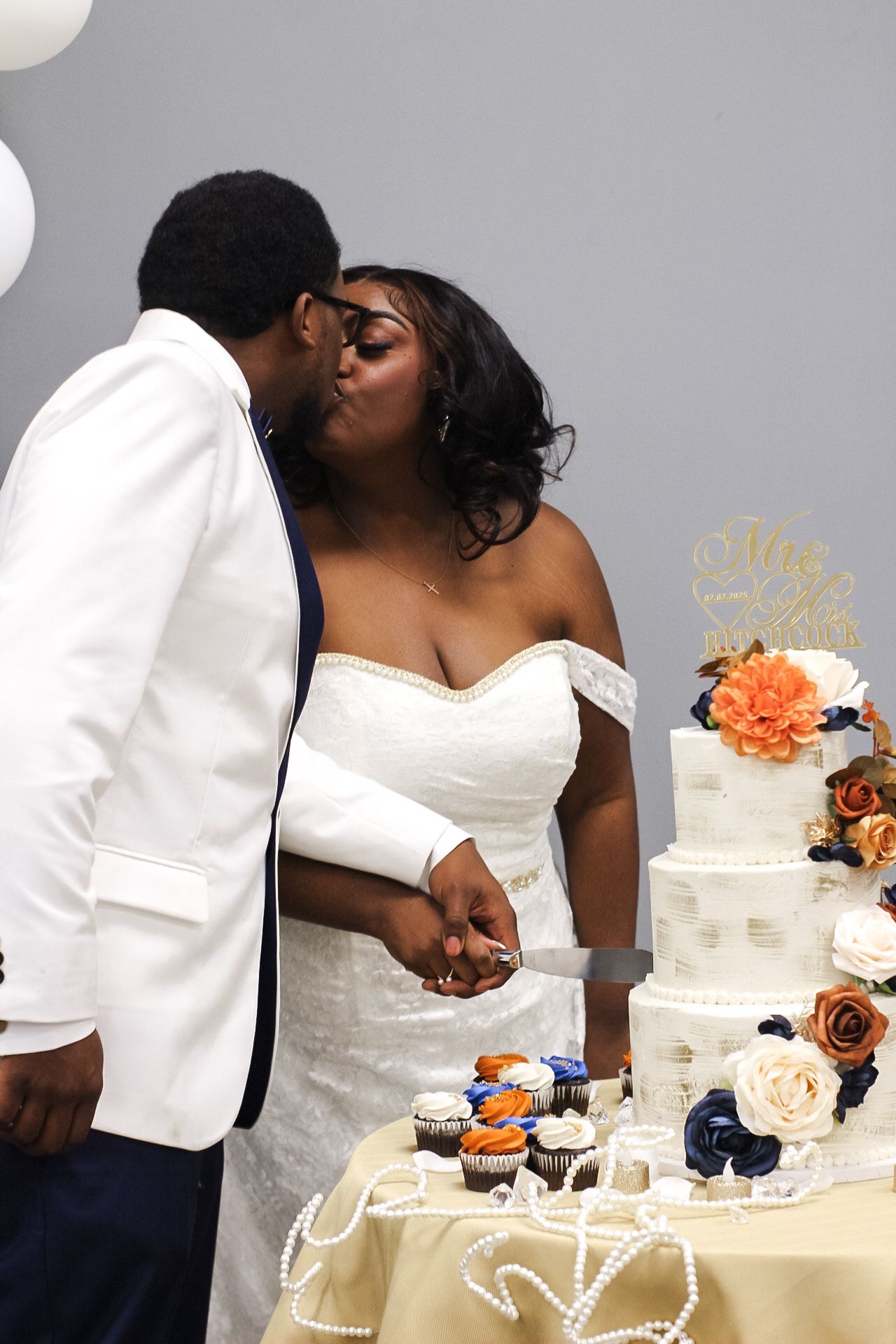 Couple shares an intimate moment while cutting their orange and white wedding cake.