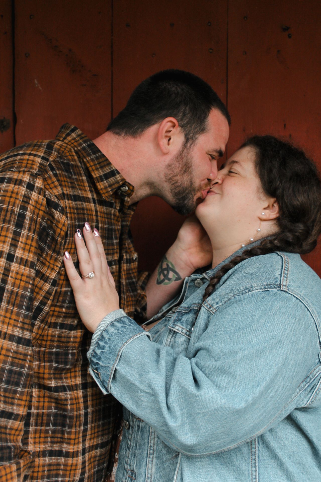 Intimate moment between couple against rustic red wooden wall background.