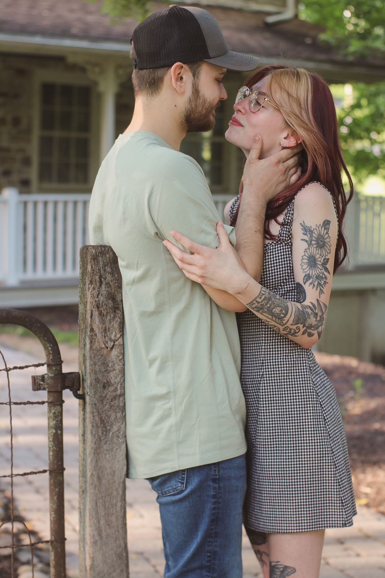 Couple sharing an intimate moment by a tree near historic stone building.