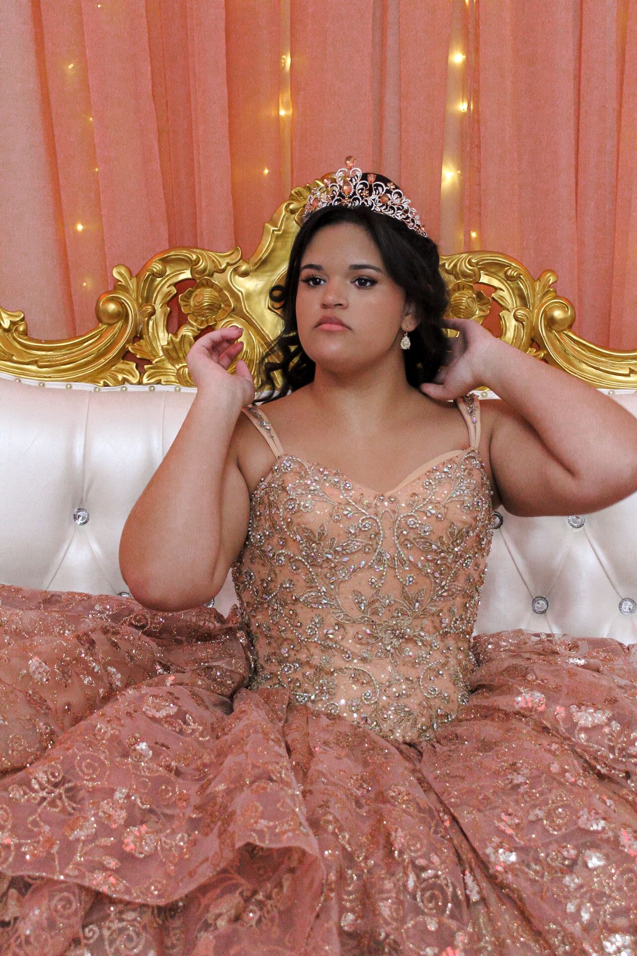 Close-up portrait showing intricate beadwork of rose gold quinceañera gown and crown.