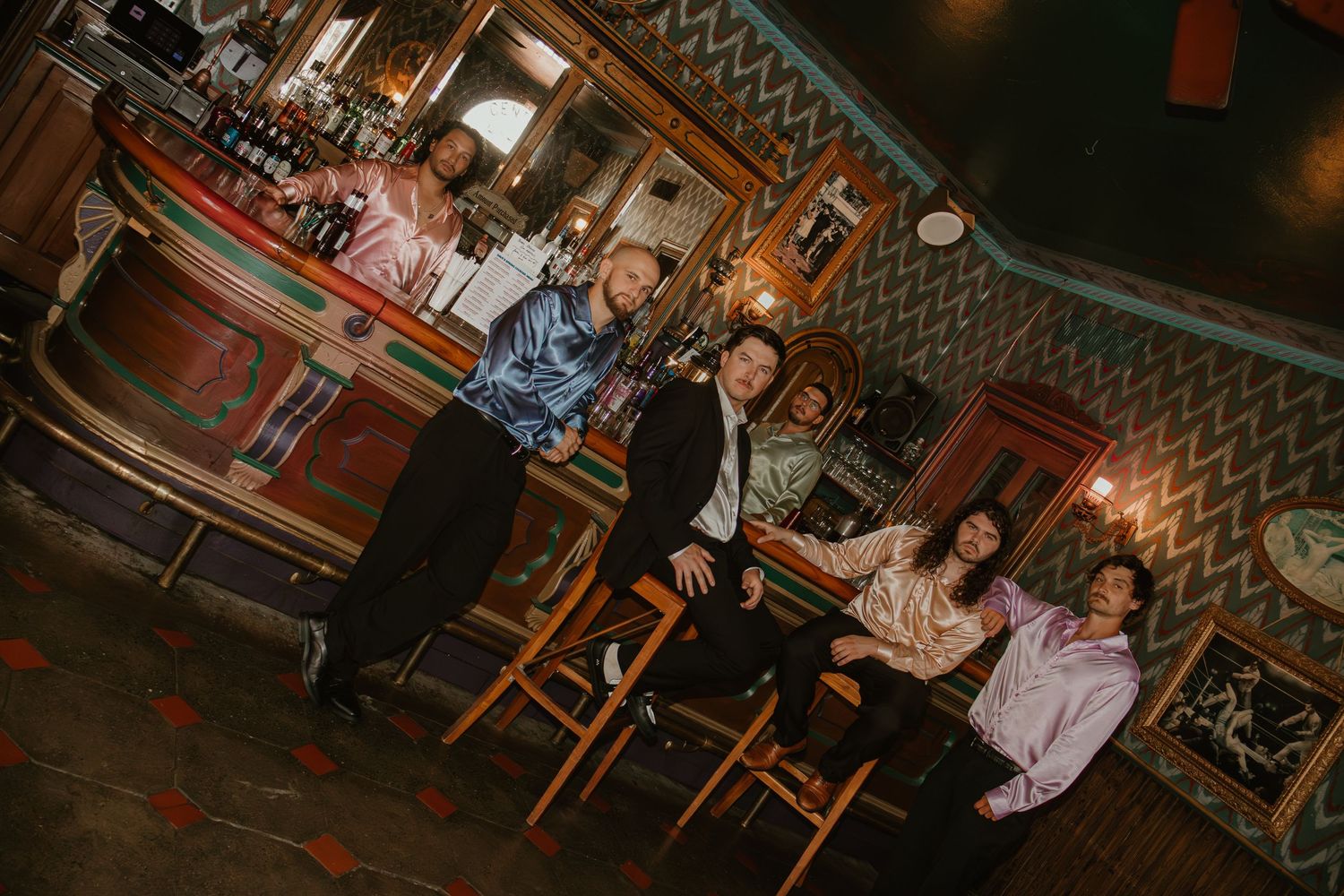 Group of friends posing and smiling together inside a vintage bar with colorful decor and warm lighting.