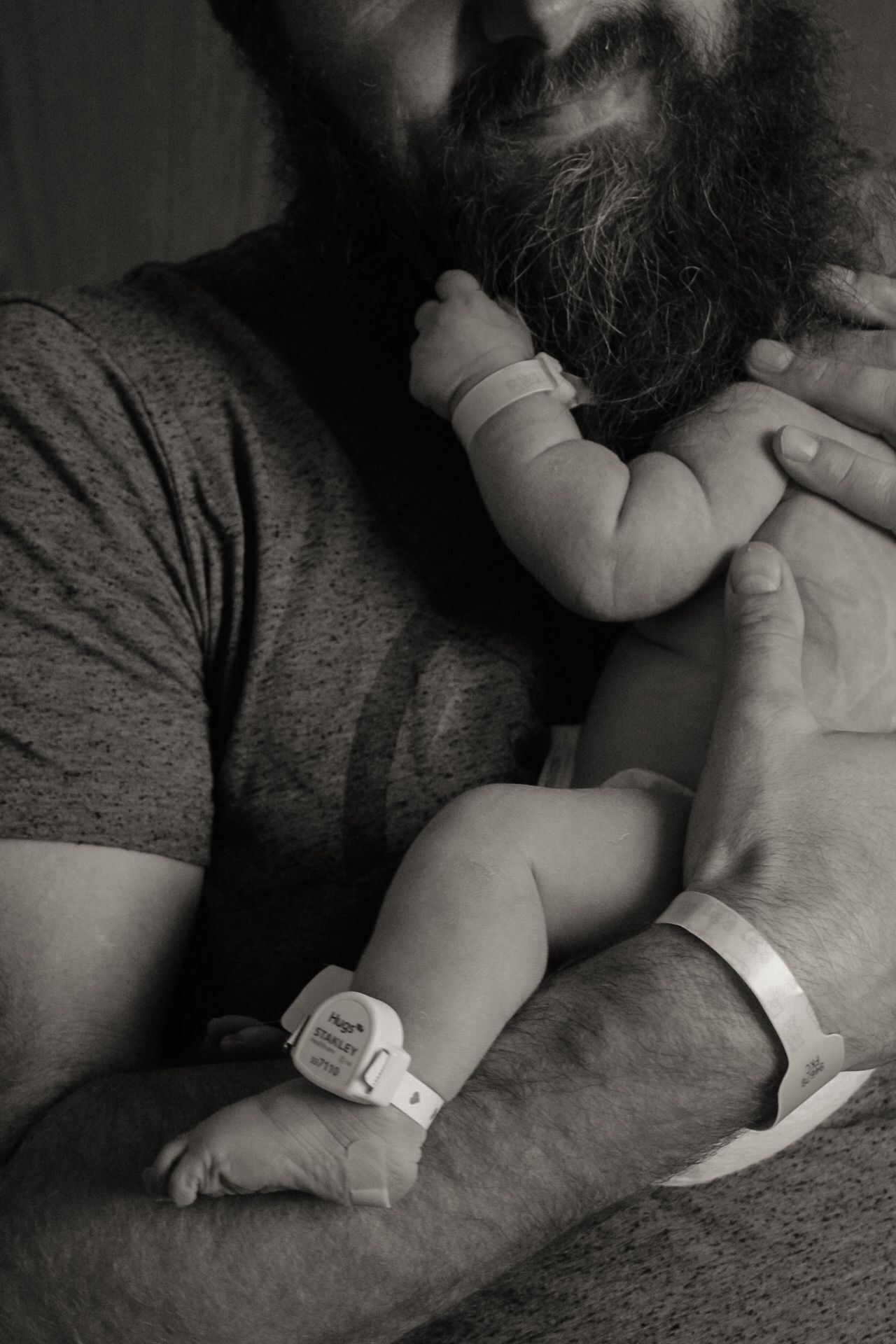 Intimate black and white portrait of a bearded person with an infant.