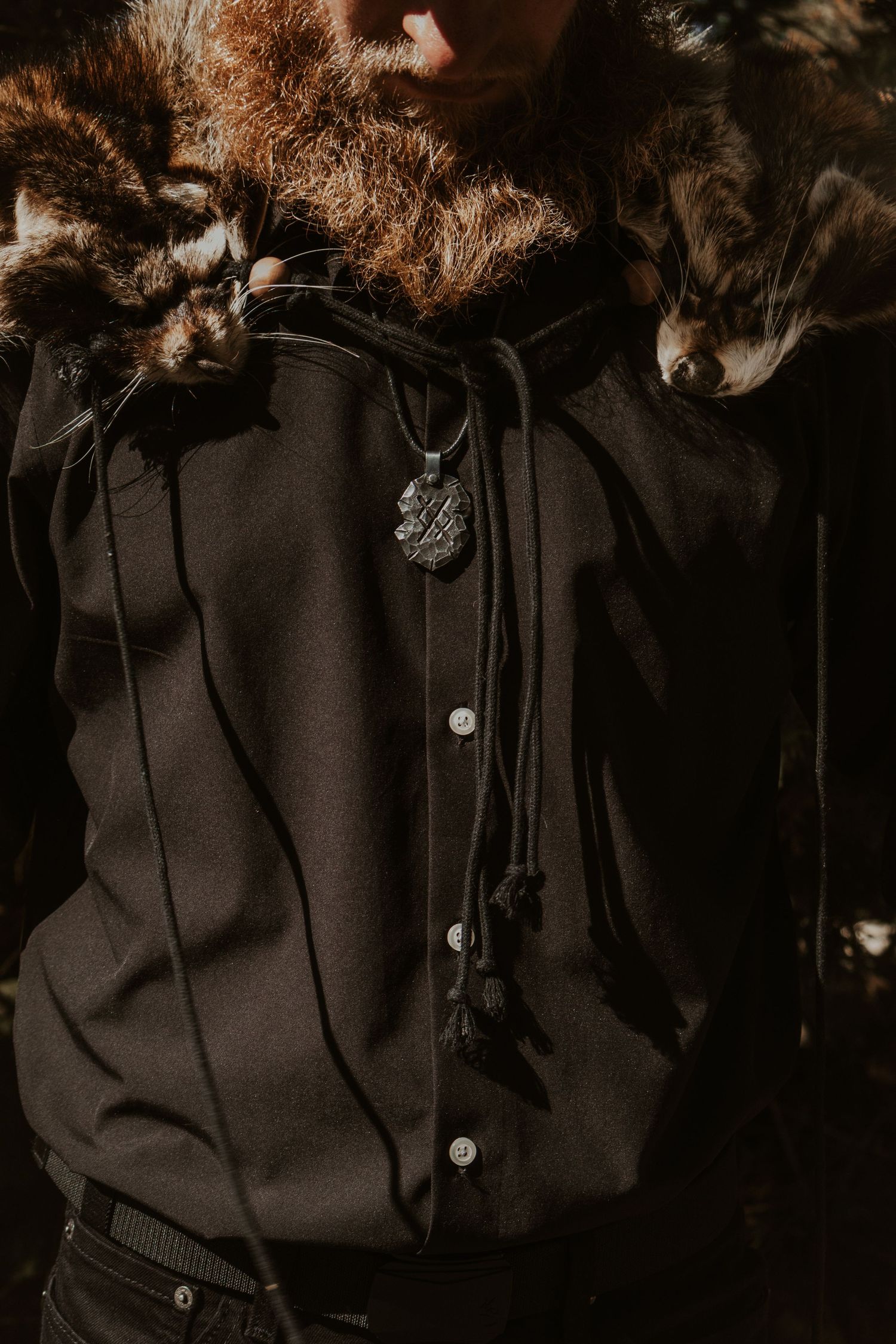 A close-up view of black buttons on a dark fabric garment against a shadowy background.