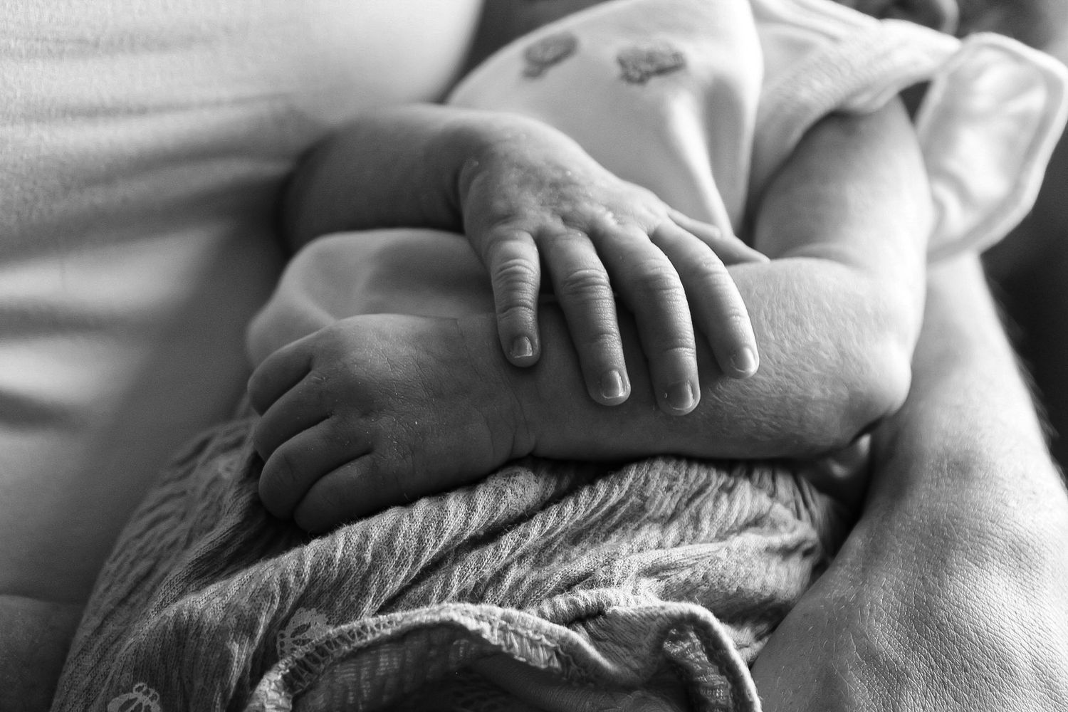 Close-up black and white details of hands tenderly touching skin.