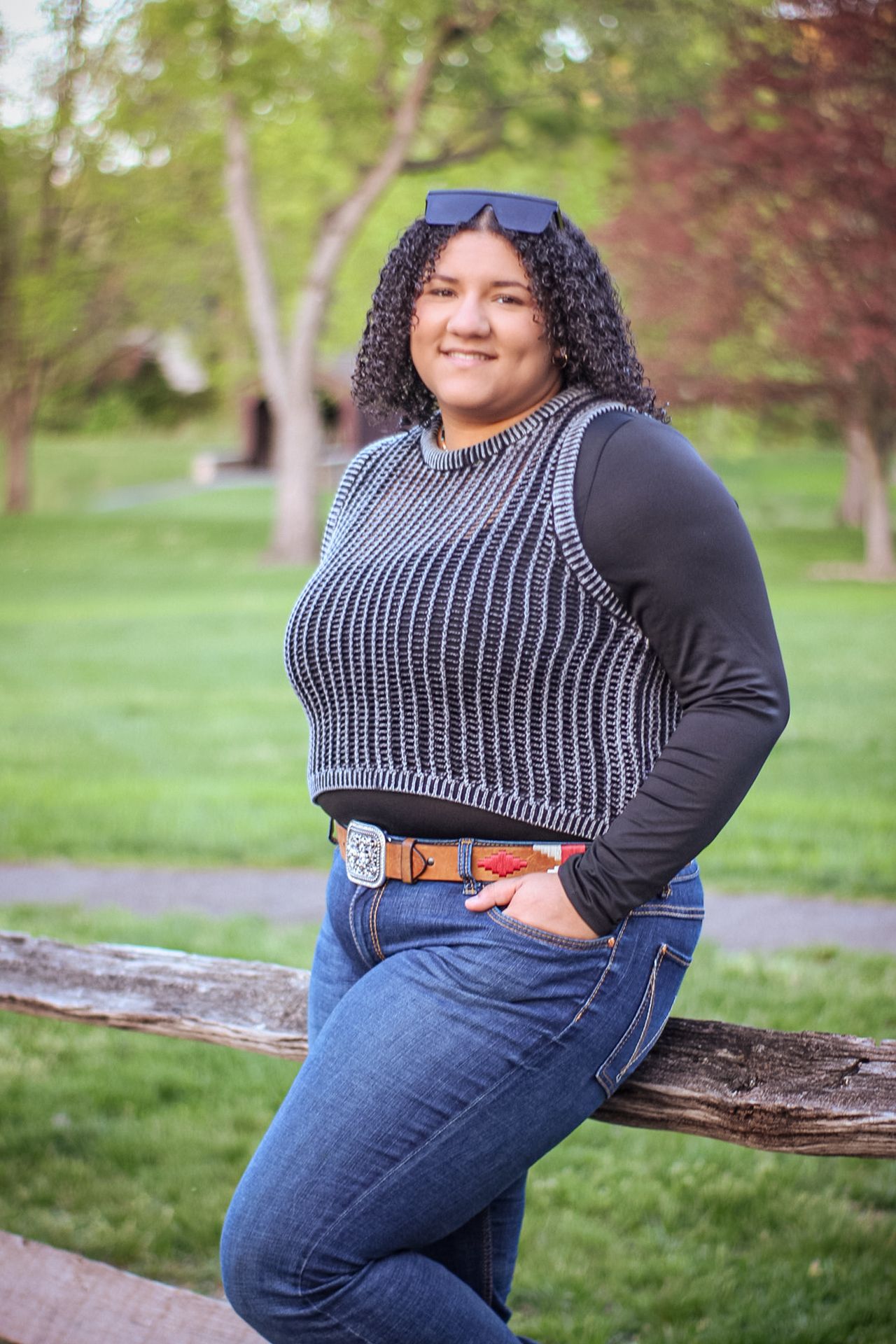 Casual outdoor photo on grass wearing striped knit top, jeans and brown belt.