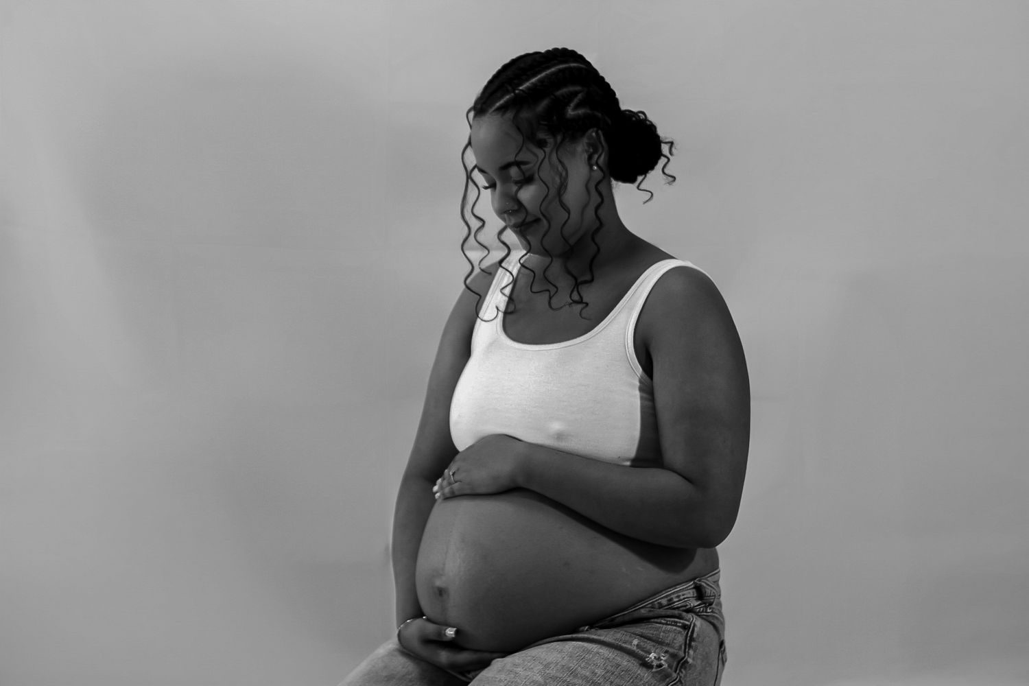 Black and white maternity photo showing contemplative moment with pregnant person.