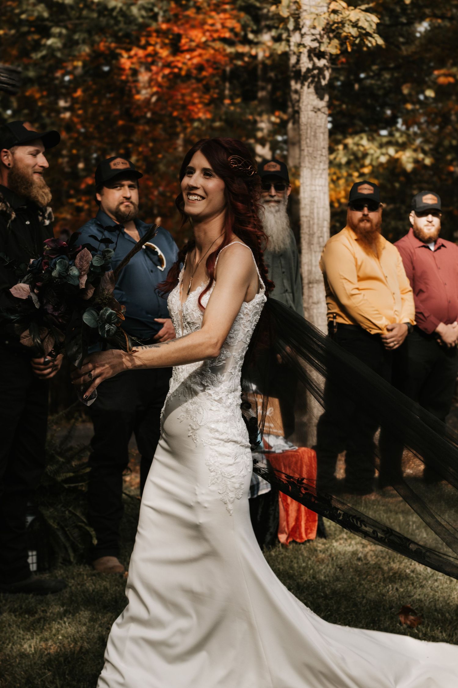 A couple shares a joyful dance moment during their wedding celebration surrounded by autumn foliage and guests.