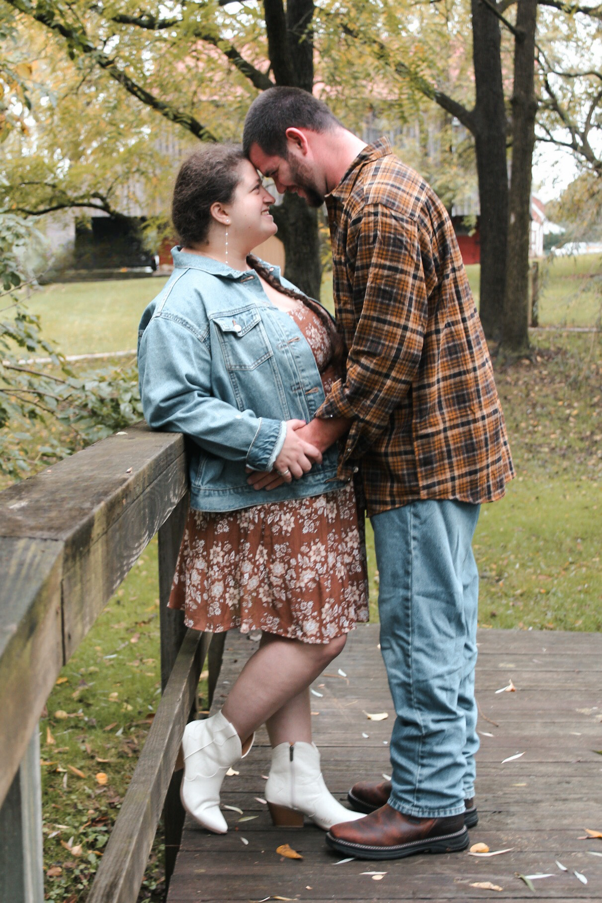 Couple sharing intimate moments on a stone pathway surrounded by autumn trees and fallen leaves.