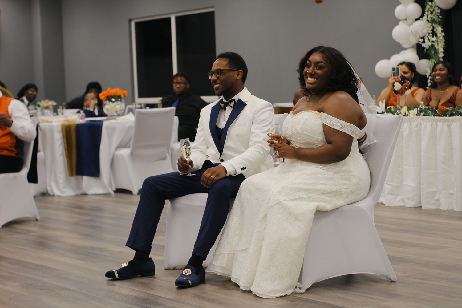 Wedding couple sits together during their reception with orange and white decor.