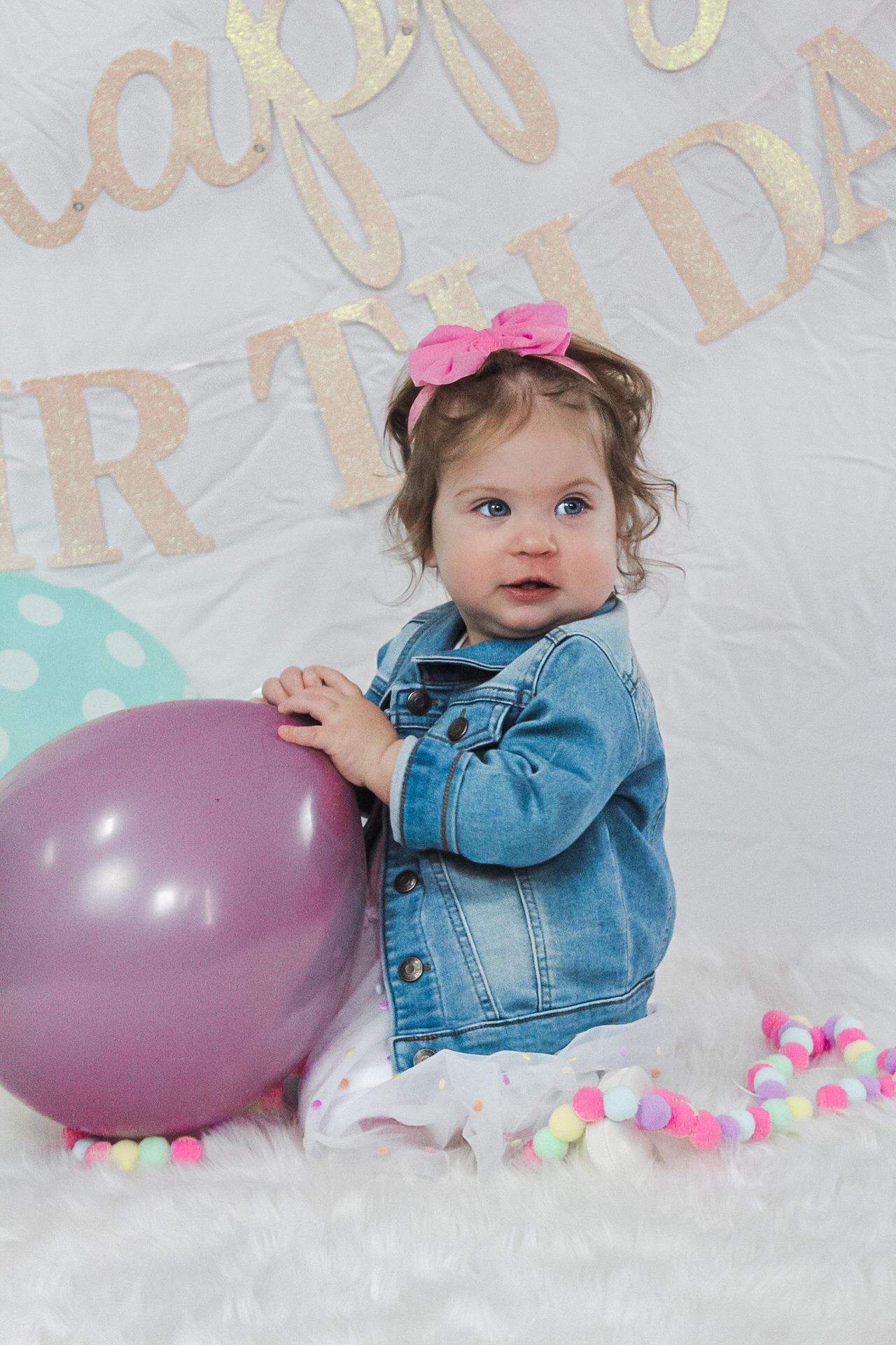 Birthday celebration scene with purple balloons and denim jacket against a light backdrop.