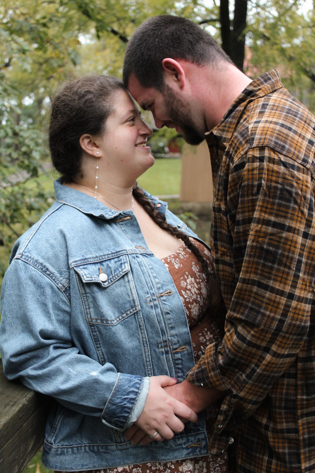 Candid romantic moment between couple wearing denim jacket and plaid shirt.