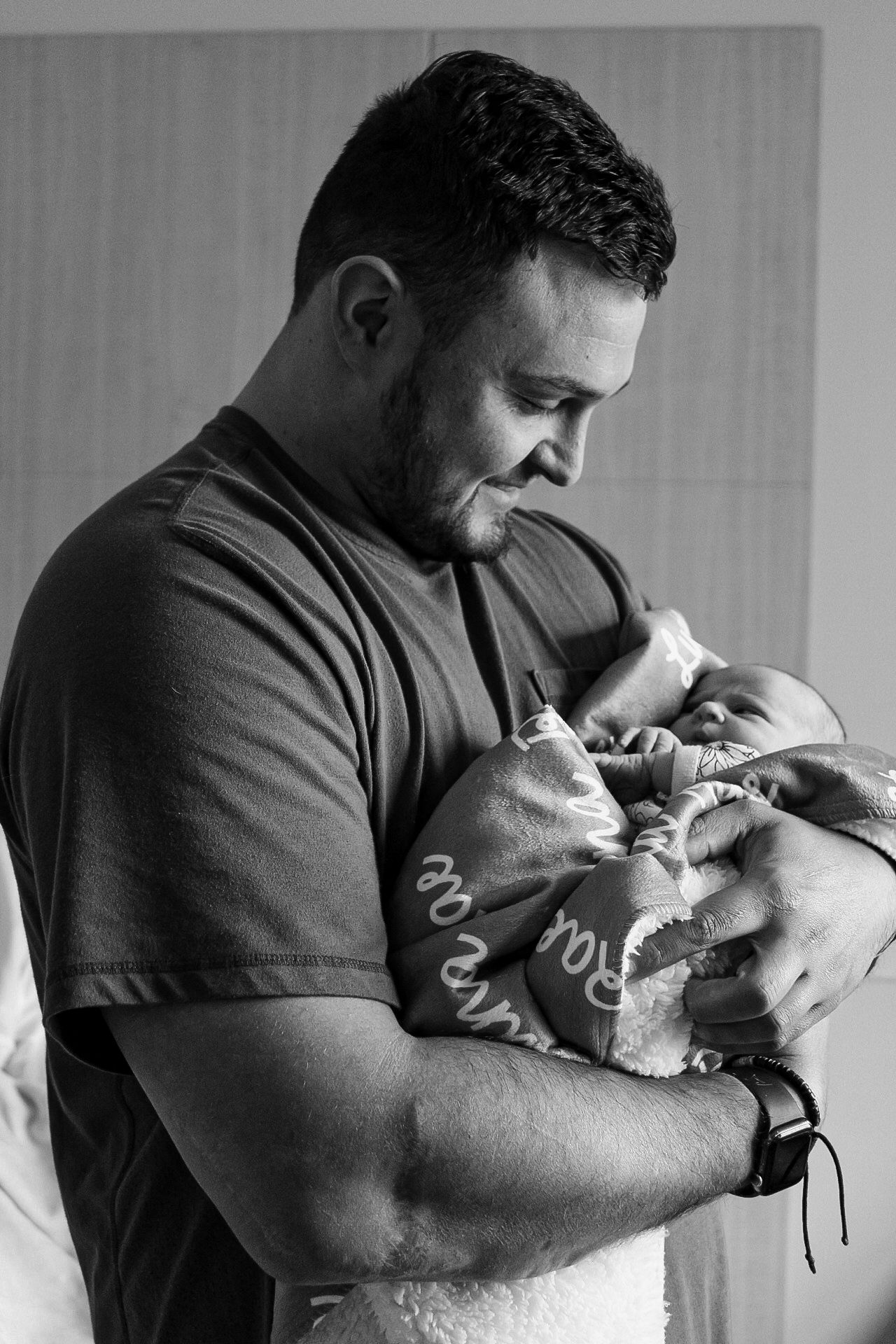 A tender moment captured in black and white as a parent cradles and gazes lovingly at their newborn baby.