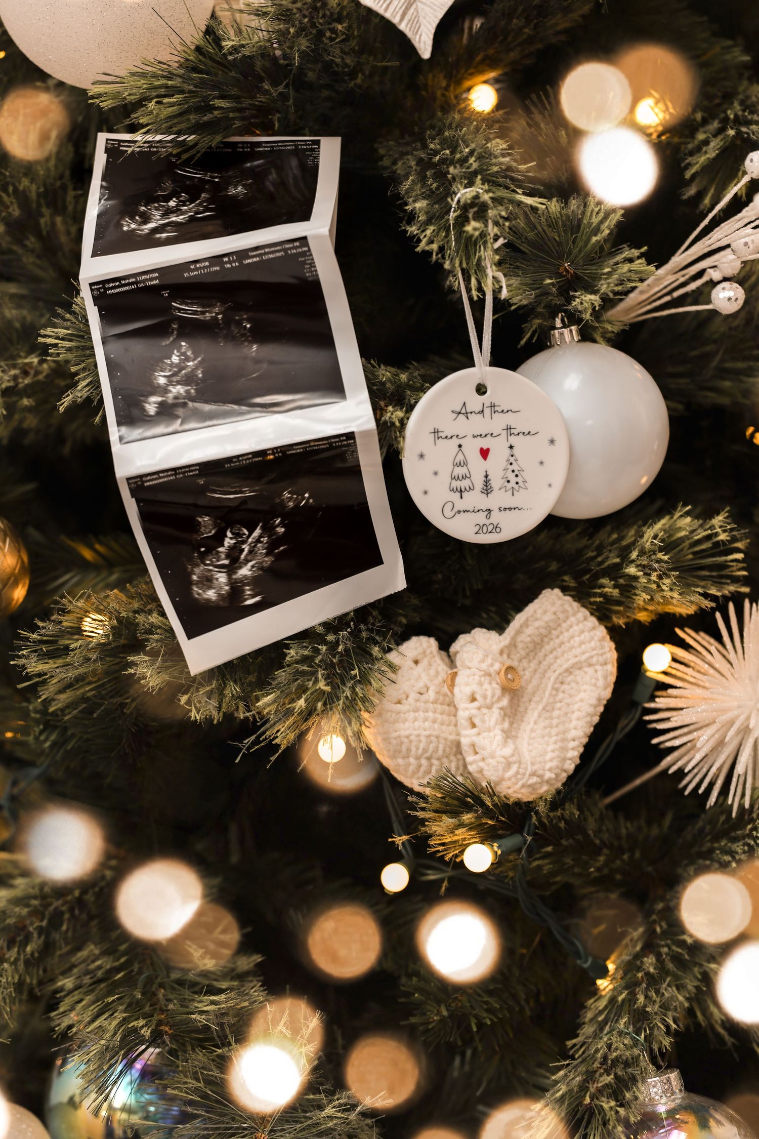 Christmas tree decorated with ultrasound photos, baby booties, and a pregnancy announcement ornament.