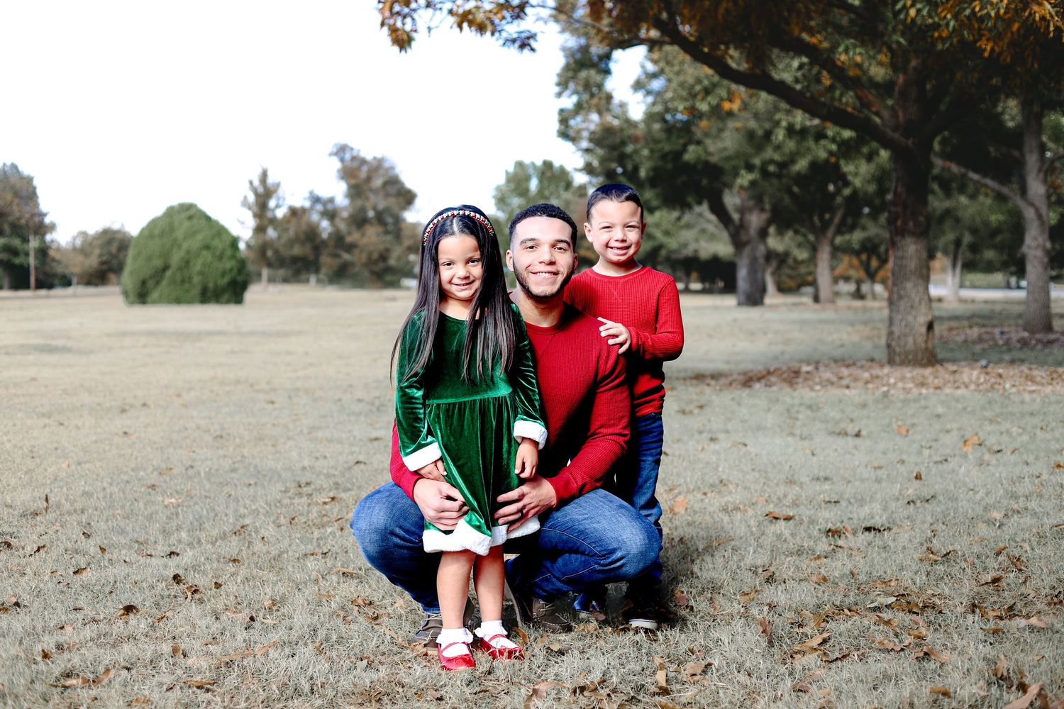 Family members in coordinated holiday outfits gather for outdoor photos on fallen leaves.