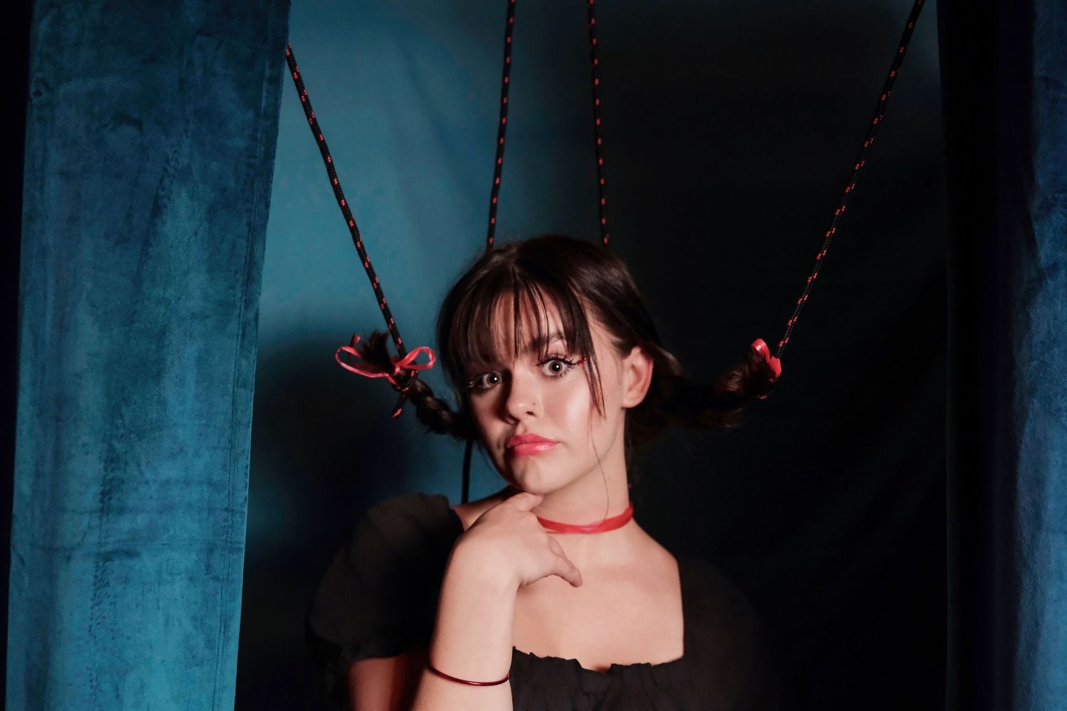 Dramatic portrait with red accents and chains against dark blue background.