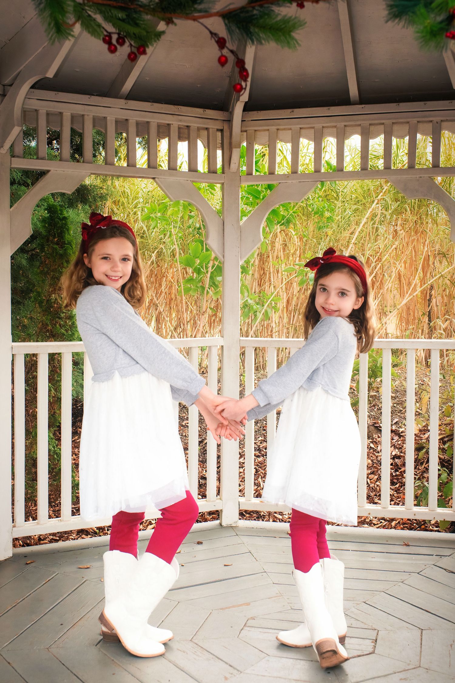 A figure in a white dress and red accessories twirls playfully in a white gazebo during a photo session.