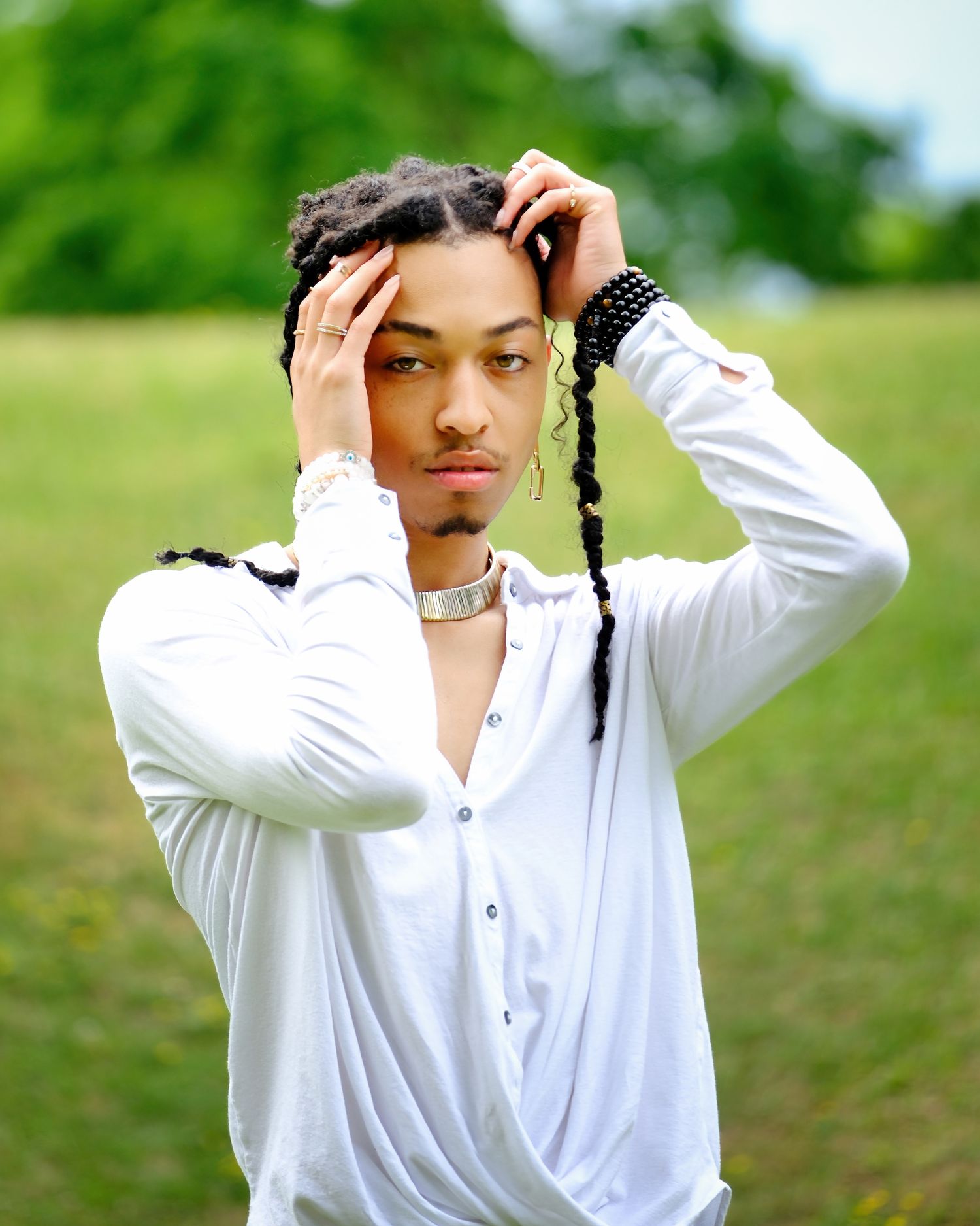 Portrait of a person in white shirt posing outdoors against a green natural background.