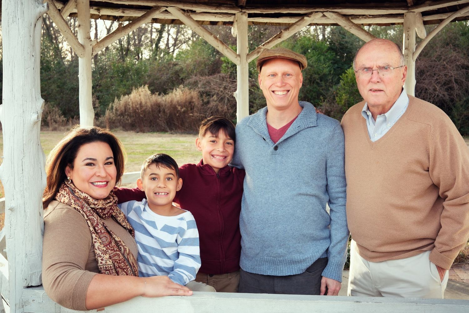 Multi-generational family gathering under a covered porch on a sunny day.