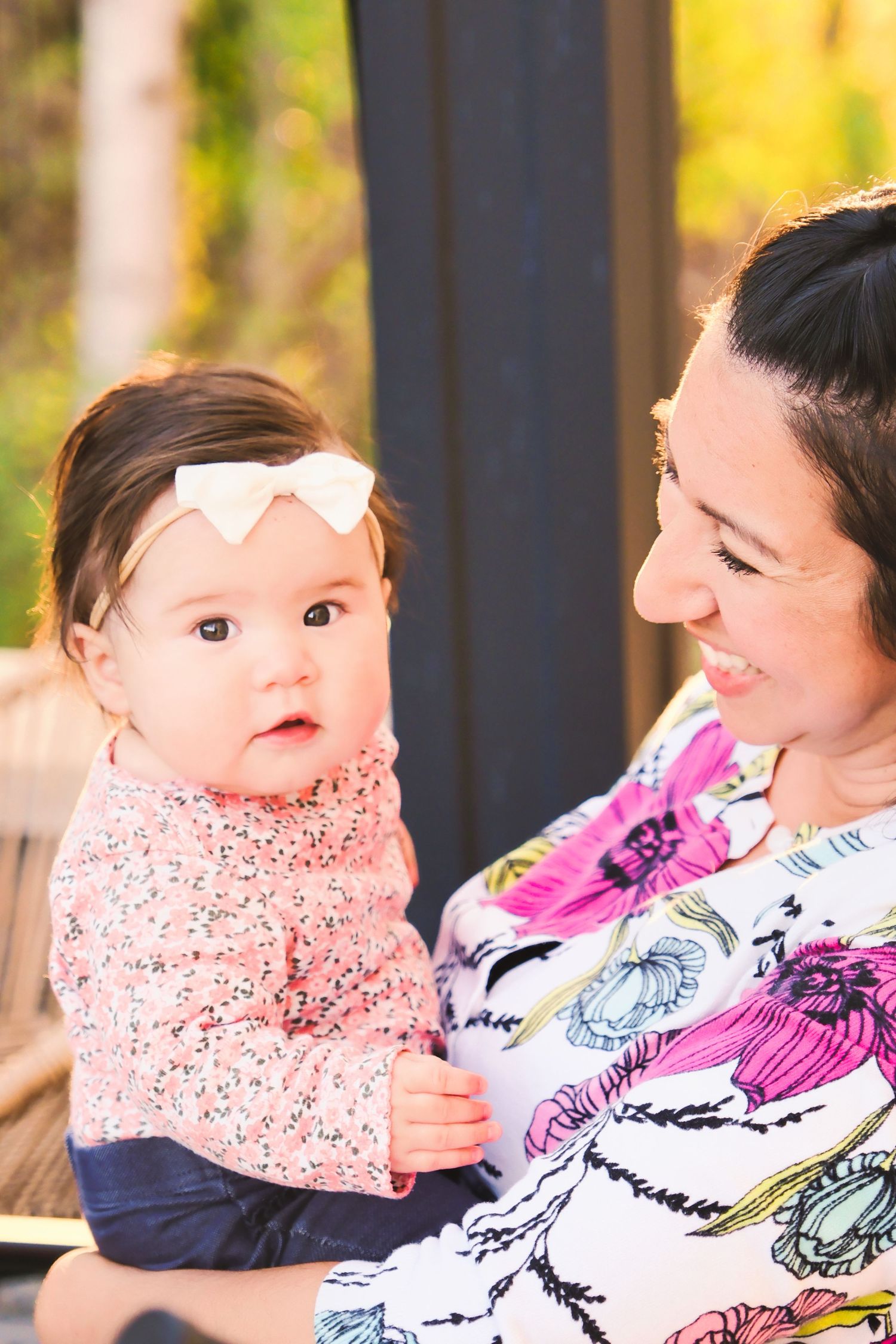 A series of sweet moments showing a baby in a pink bib being held and cuddled outdoors with autumn colors in background.