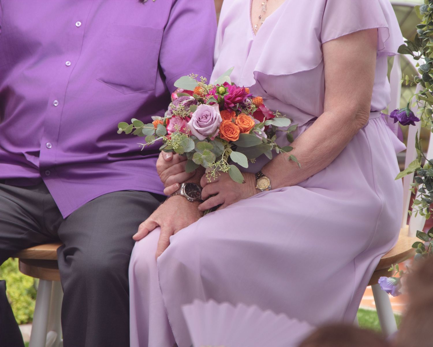 A colorful floral bouquet with pink and orange blooms held during a wedding ceremony.