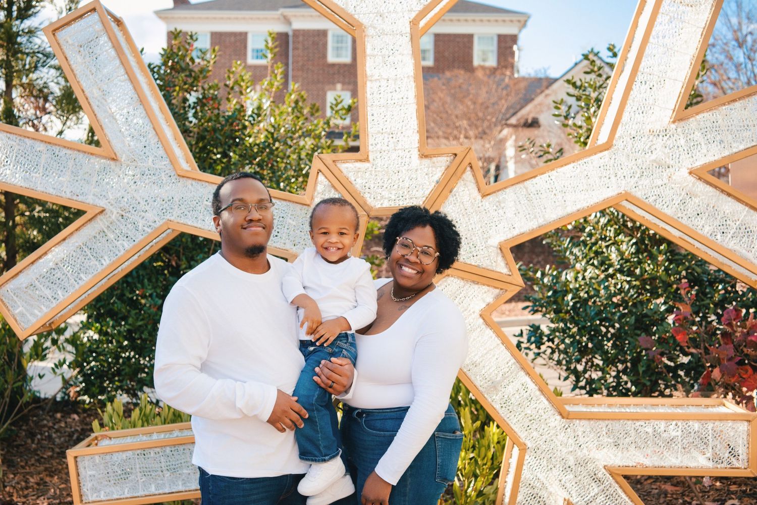 Family poses together inside large illuminated snowflake decoration frame.