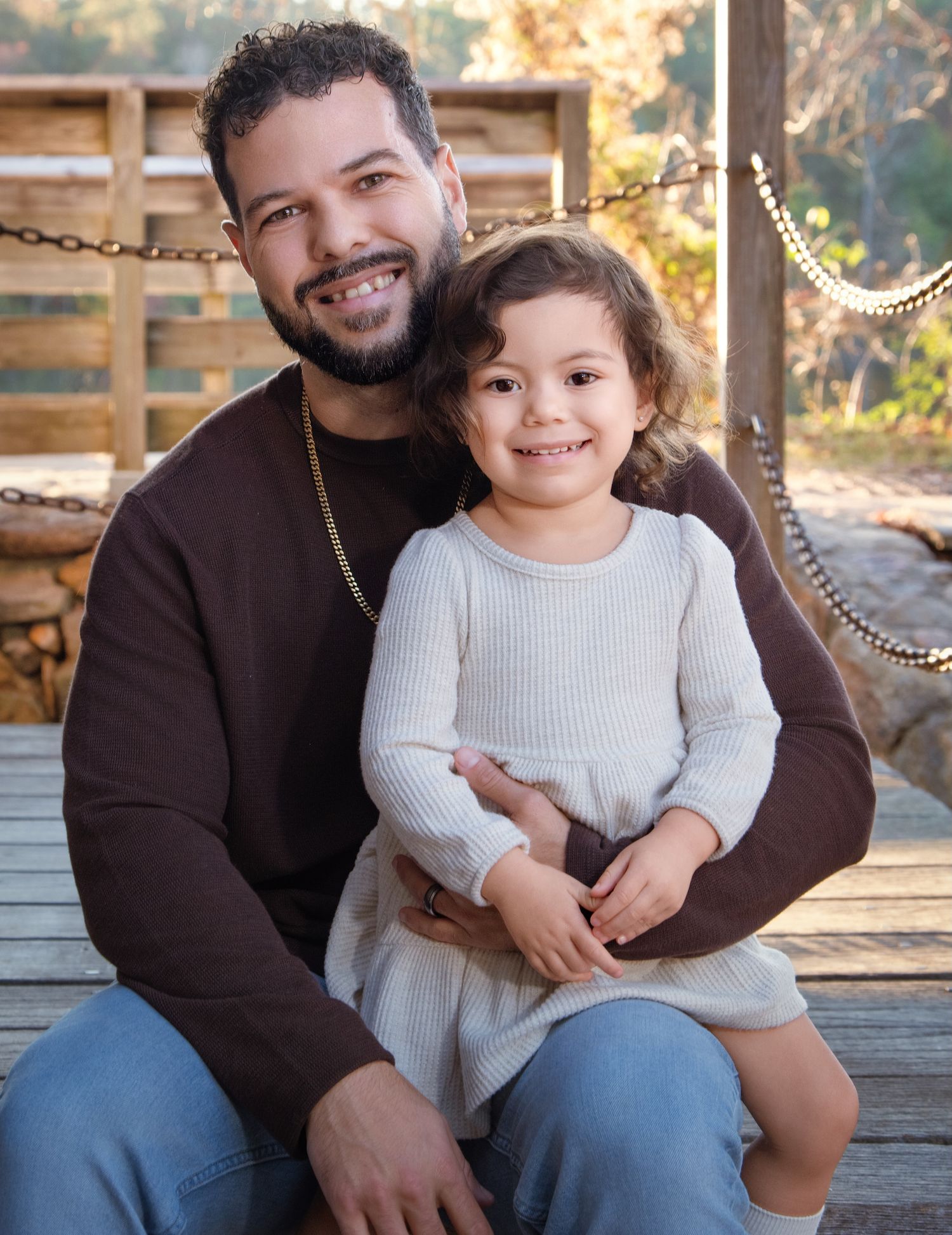 Parent and child portrait on wooden deck during golden hour.