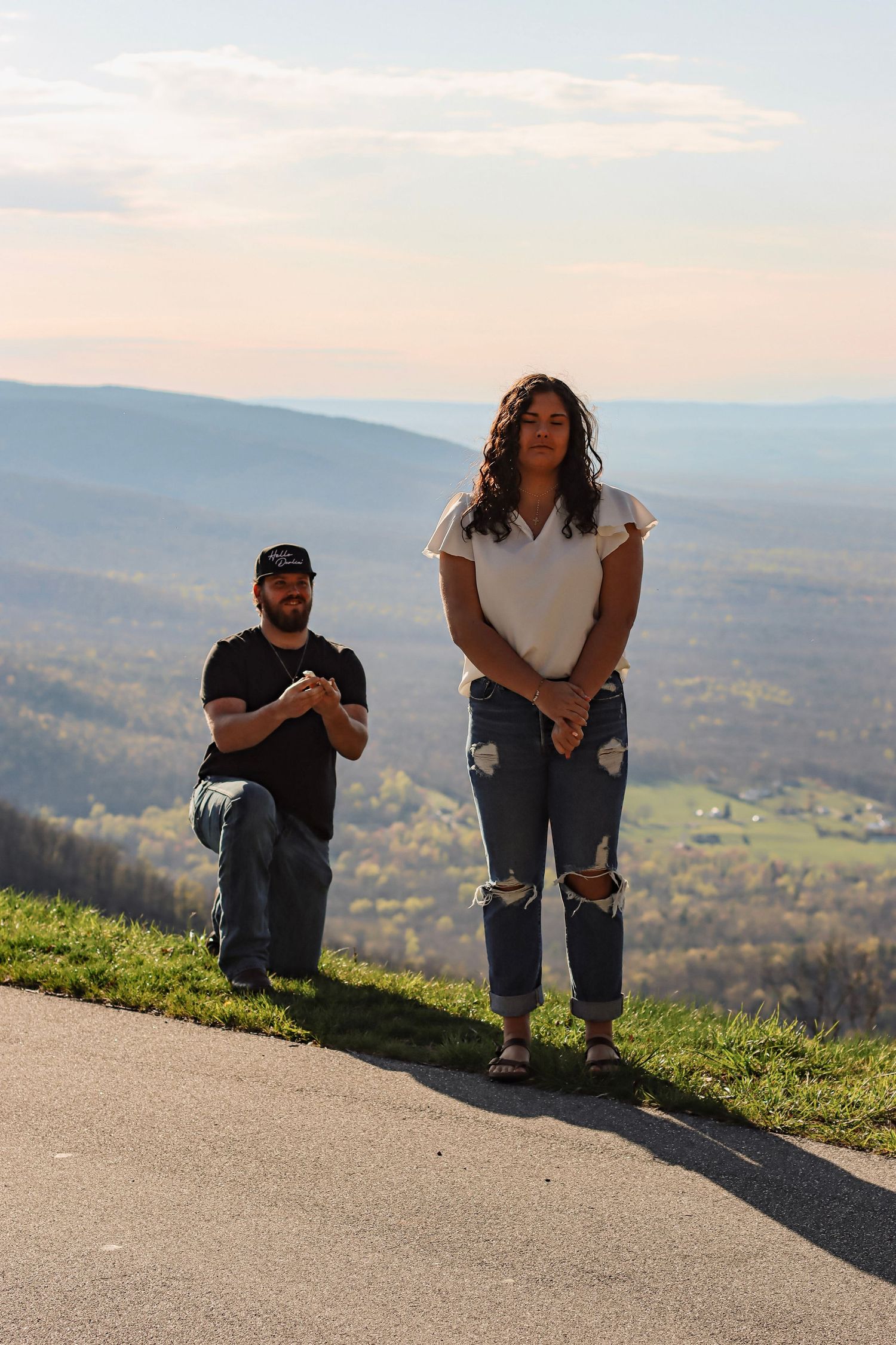 Couple posing on a scenic overlook with rolling mountain valley views at golden hour.