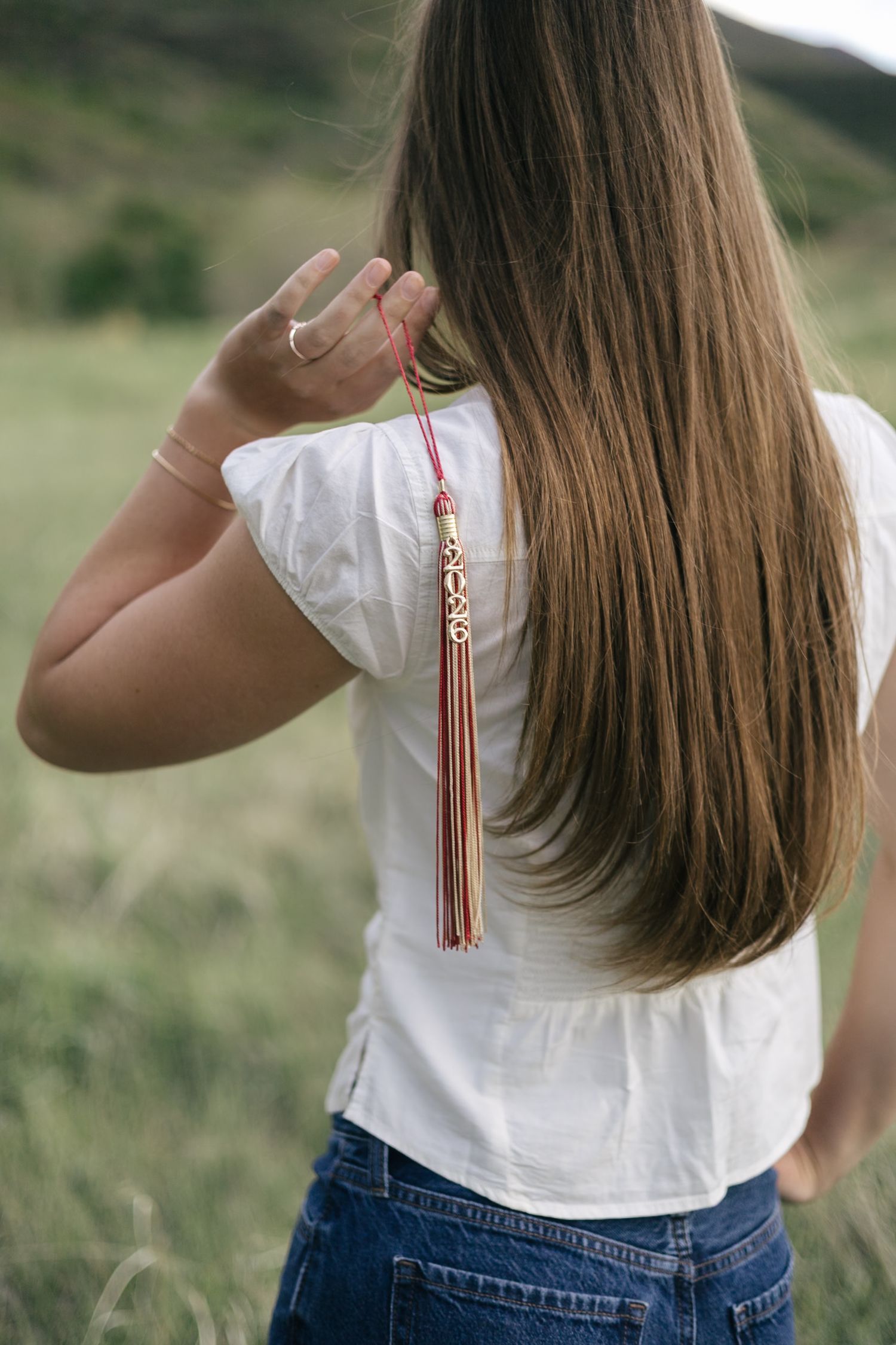 senior girl posing in a field, with tassel over her shoulder
