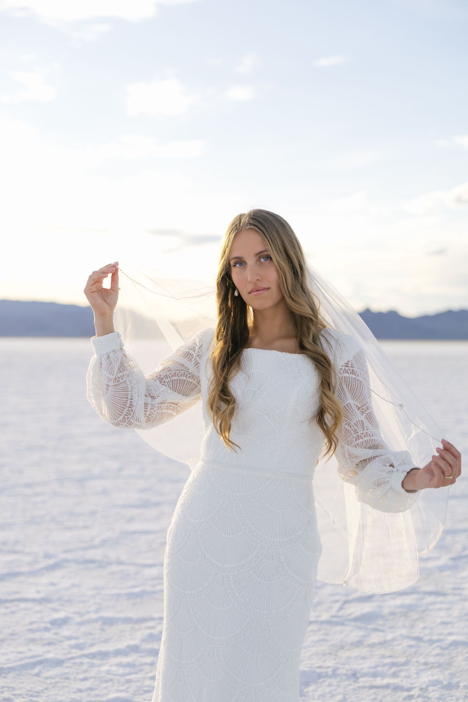 bride on the Utah salt flats holding out her veil