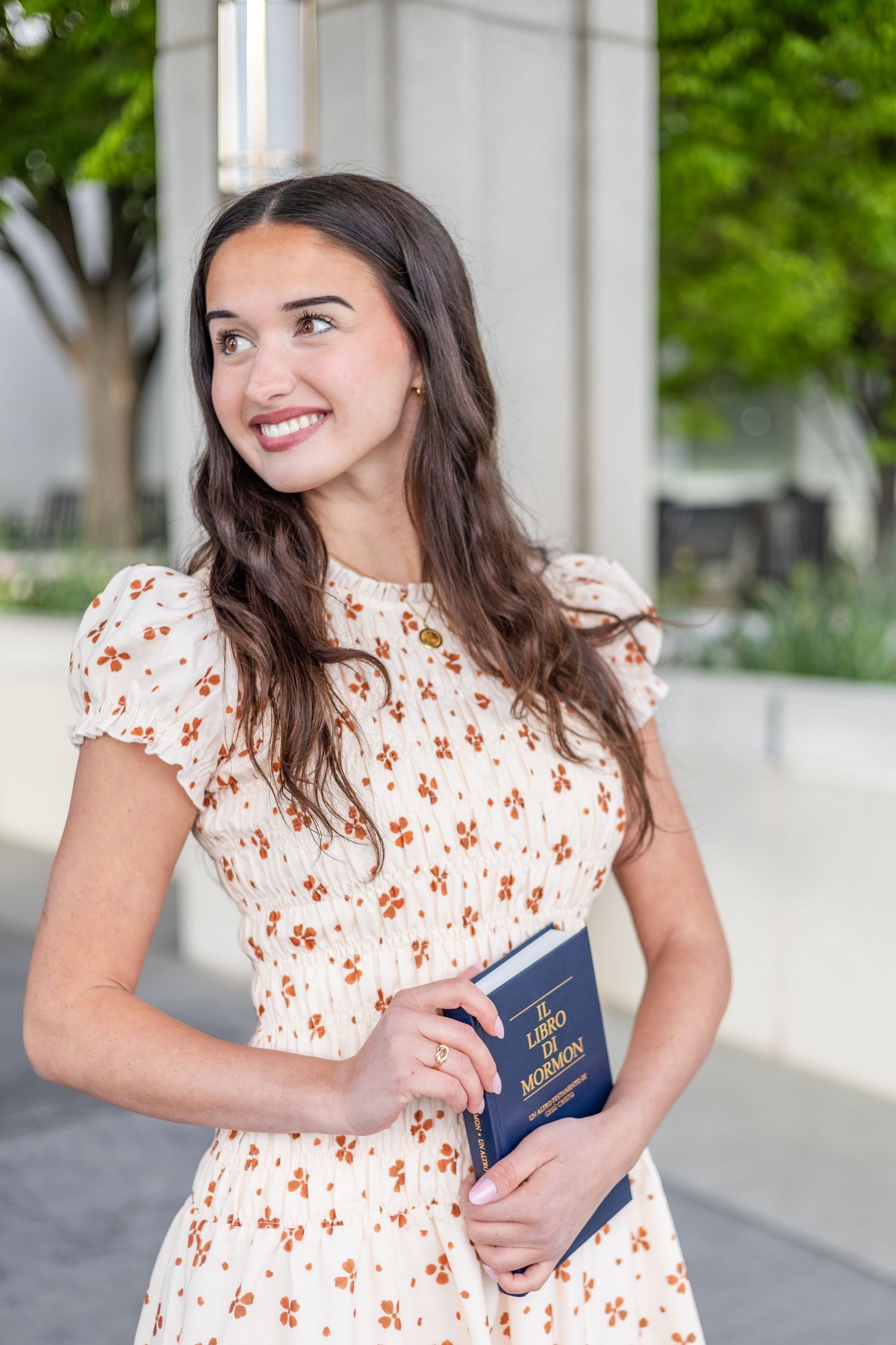 girl holding a book of scripture, posing at an LDS temple