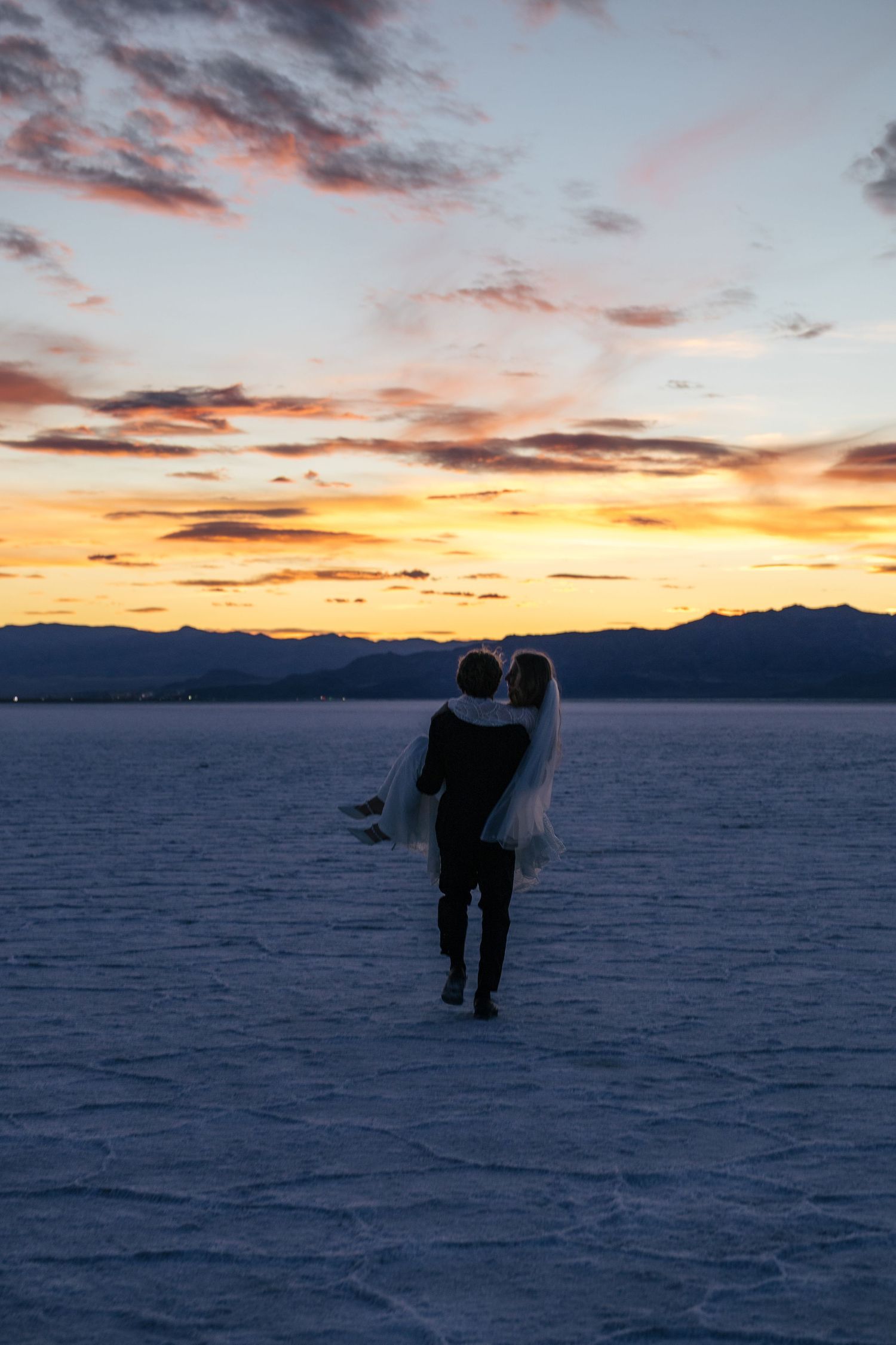 groom carrying bride on the Utah salt flats at sunset