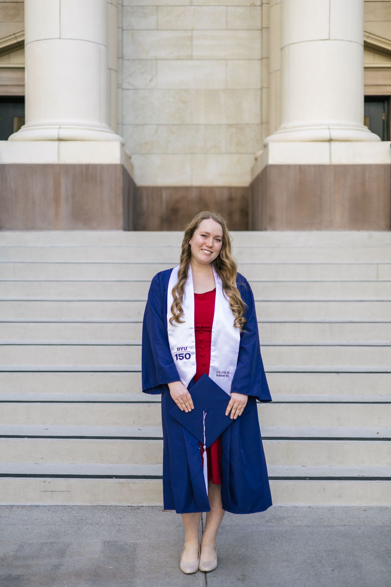byu graduate holding cap in front of steps and columns