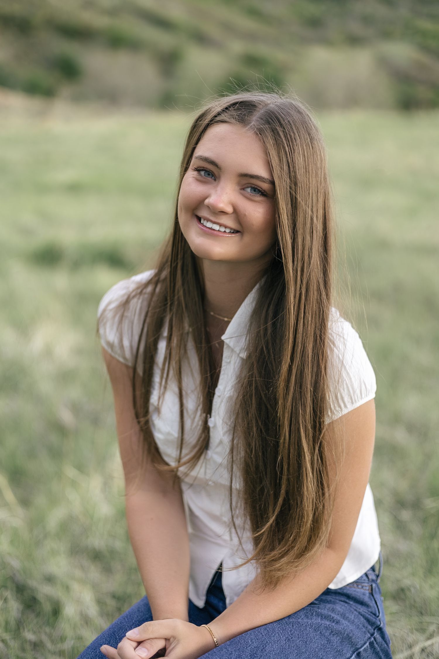 senior girl posing in a field, smiling at the camera