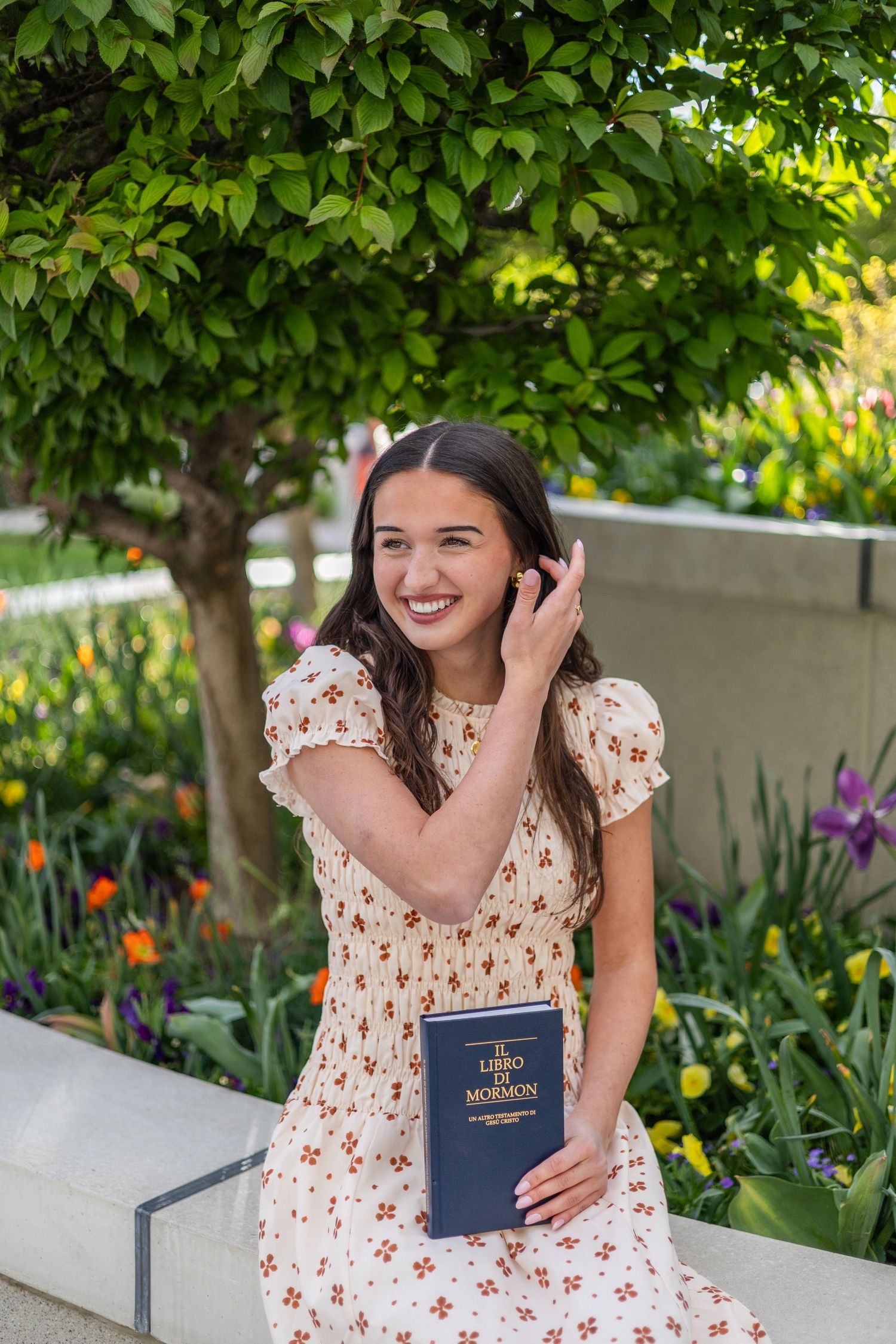 girl holding a book of scripture, smiling while sitting at an LDS temple