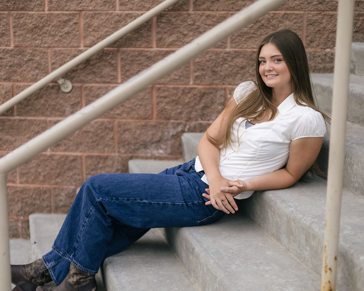 senior girl posing at her school, leaning back on the stairs